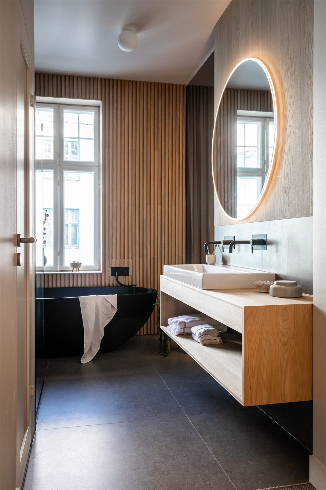 Badene har delikate storformat fliser kombinert med eik, samt badekar og dusj. Galleribilde