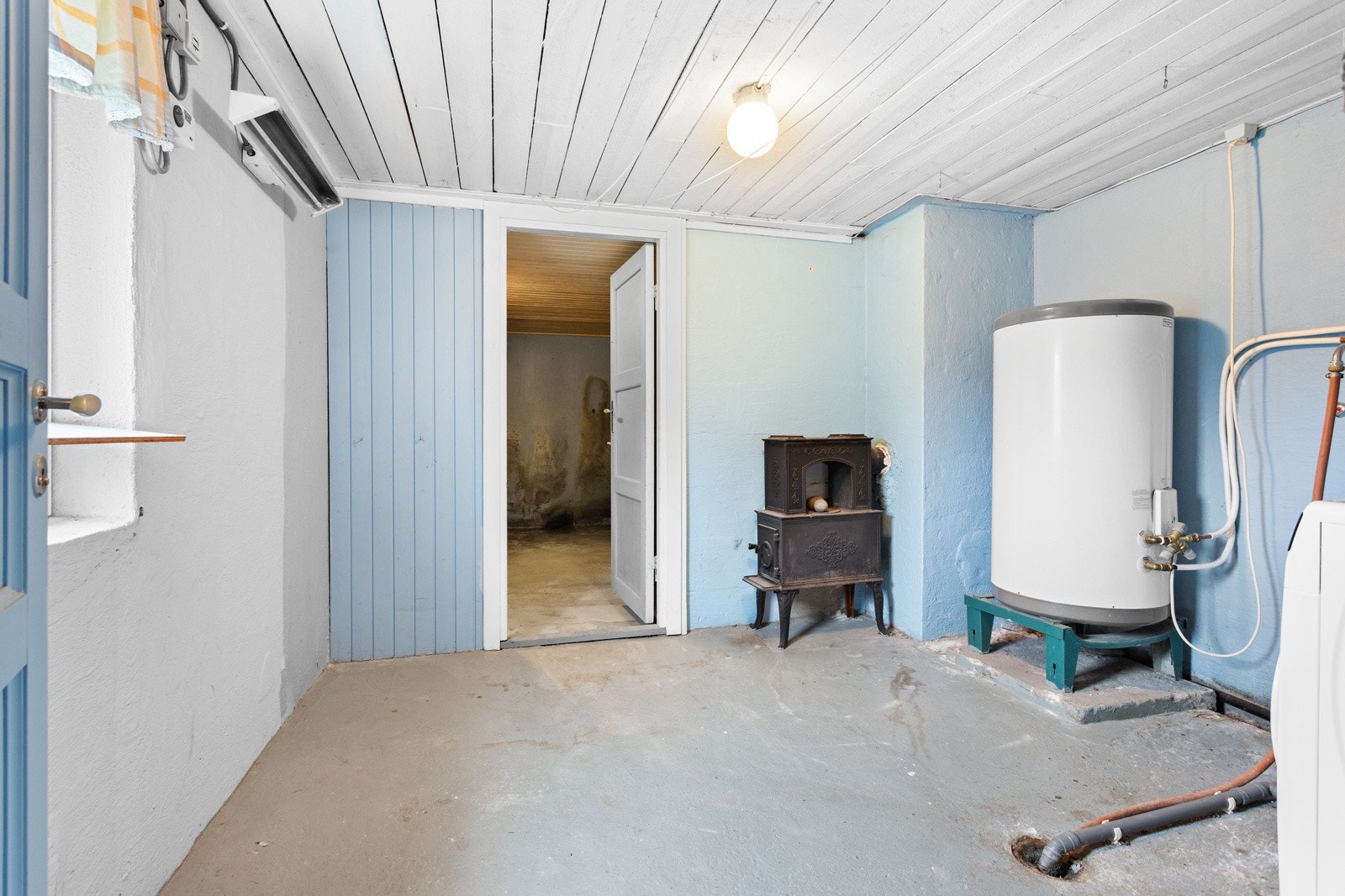 Rommet har opplegg for vaskemaskin og er utstyrt med vedovn . Galleribilde