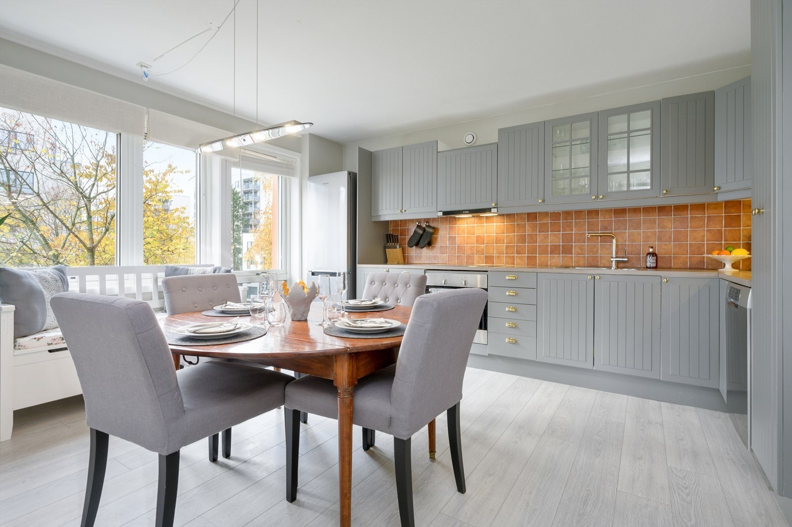 Romslig kjøkken med fronter malt i en lysgrå farge. Galleribilde