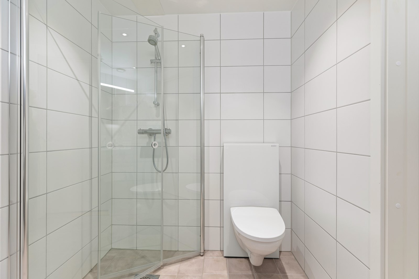 Badet har vegghengt toalett og dusjhjørne. Galleribilde