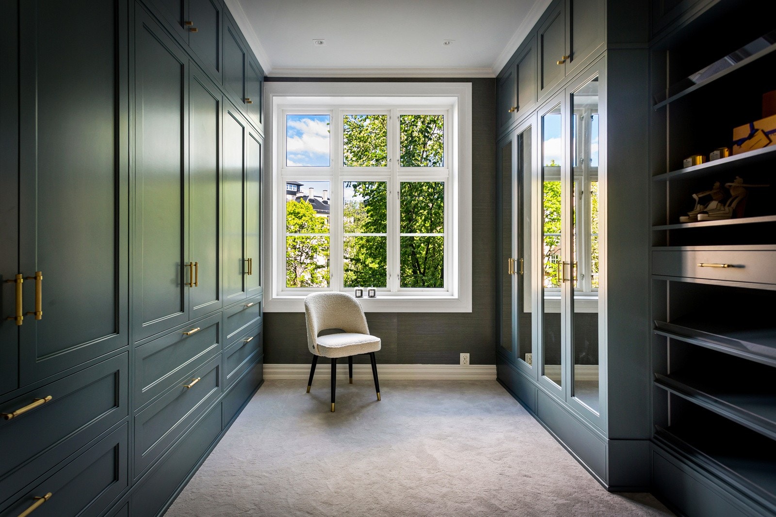 Walk-in closet har heldekkende gulvtepper, innfelte downlights og snekkertilpassede garderober fra Terna Snekkeri. Garderobeskapene går langs begge sider i rommet, og har malte rammefronter, speilfronter og hylleskap med vertikale LED-striper. Galleribilde