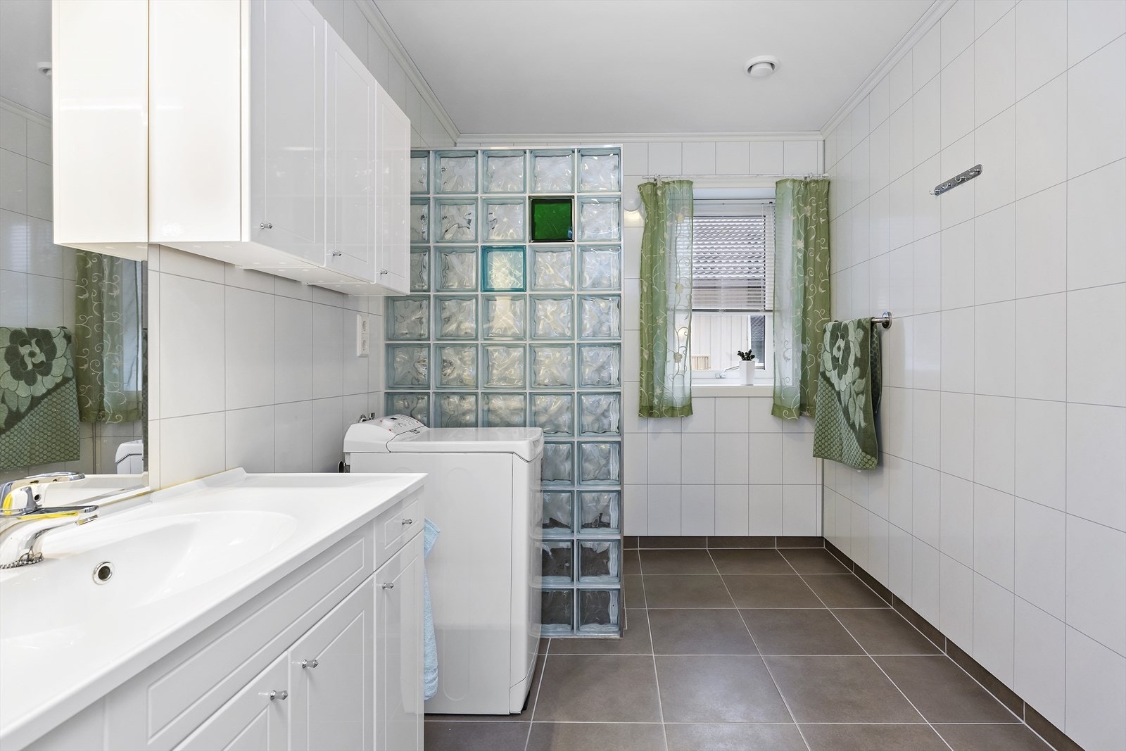 Badet har mørke fliser på gulvet og hvite våtromsplater på veggene. Galleribilde