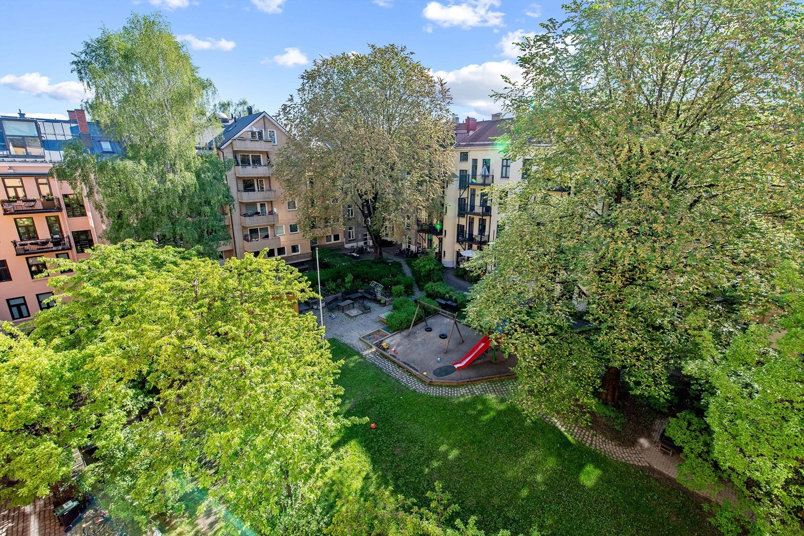 Sameiets flotte, frodige bakgård er som en lukket park med hyggelige sittegrupper og grillplass Galleribilde
