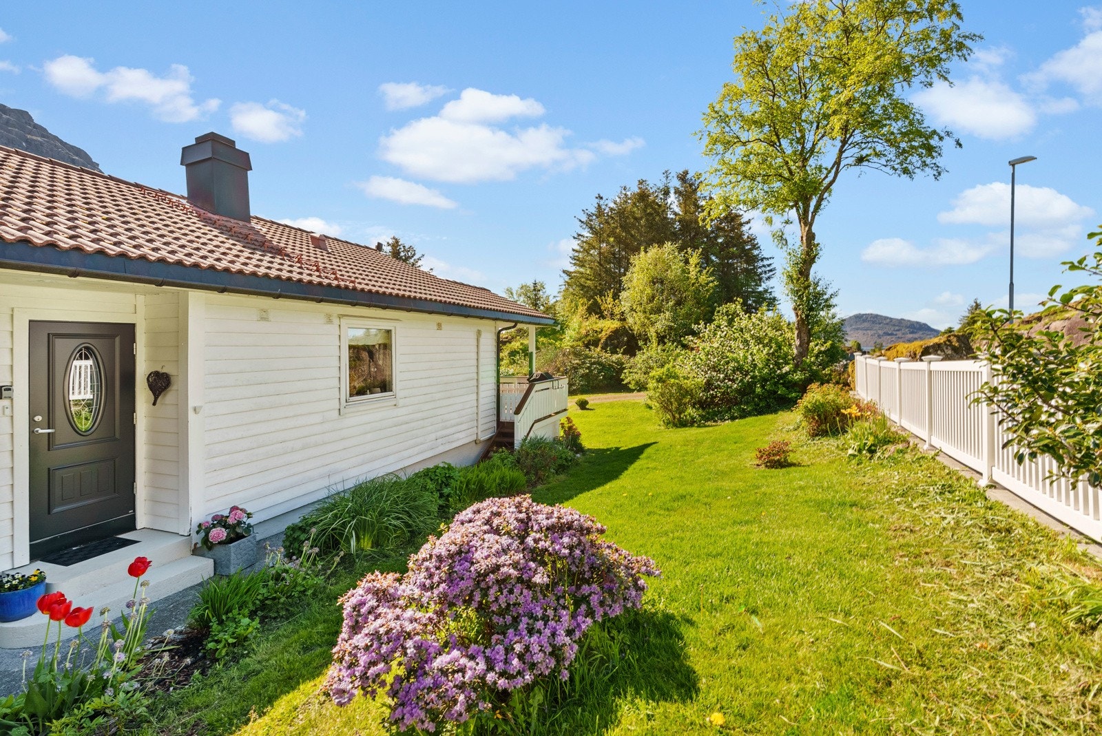 Tomta er pent opparbeidet med grøntarealer, blomsterbed og div. beplantning Galleribilde