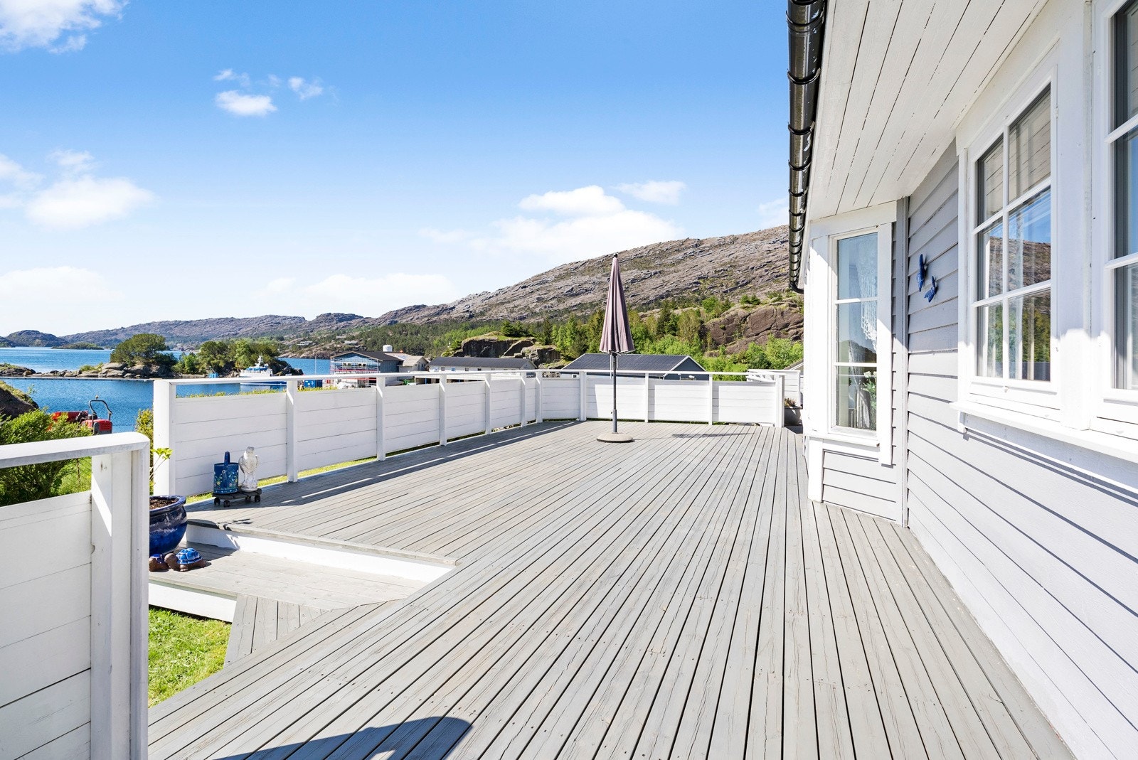 Romslig terrasse som går langs sørfasaden på boligen - Videre tilkomst til hagen Galleribilde