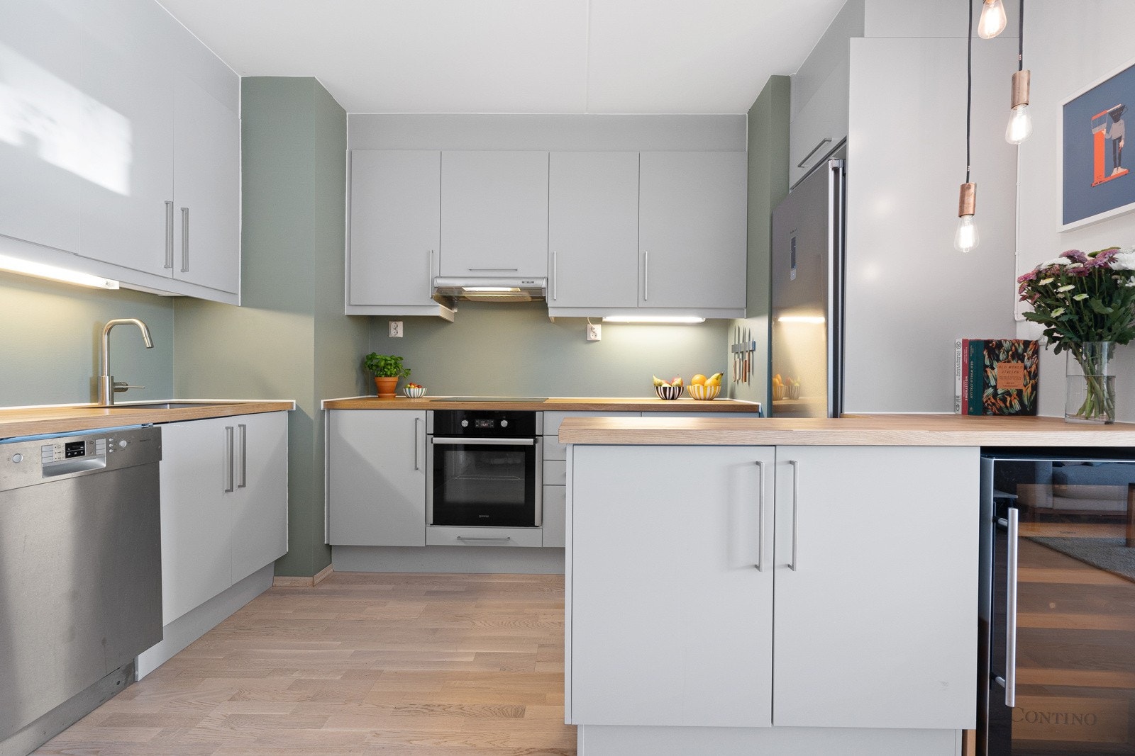 Stilrent Sigdal-kjøkken med lyse, slette fronter og eik finér benkeplate. Galleribilde