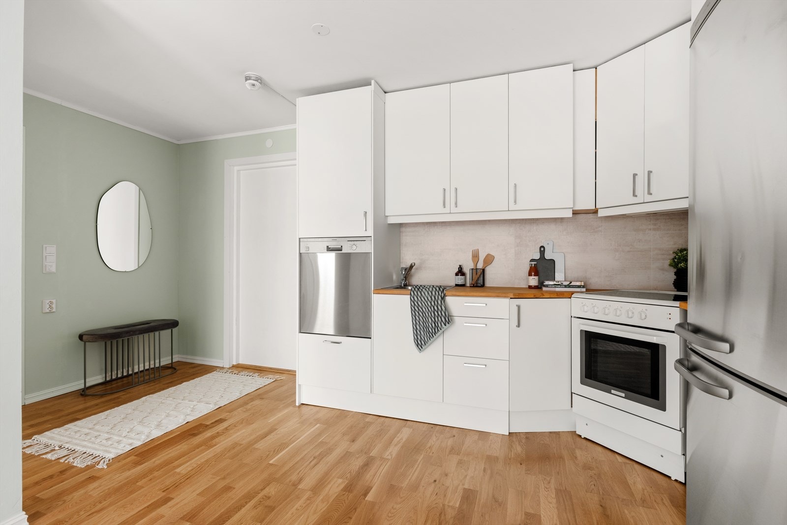 Kjøkkeninnredningen har hvite slette fronter, plater over heltre benkeplate med enkel oppvaskkum og 1 greps blandebatteri. Galleribilde