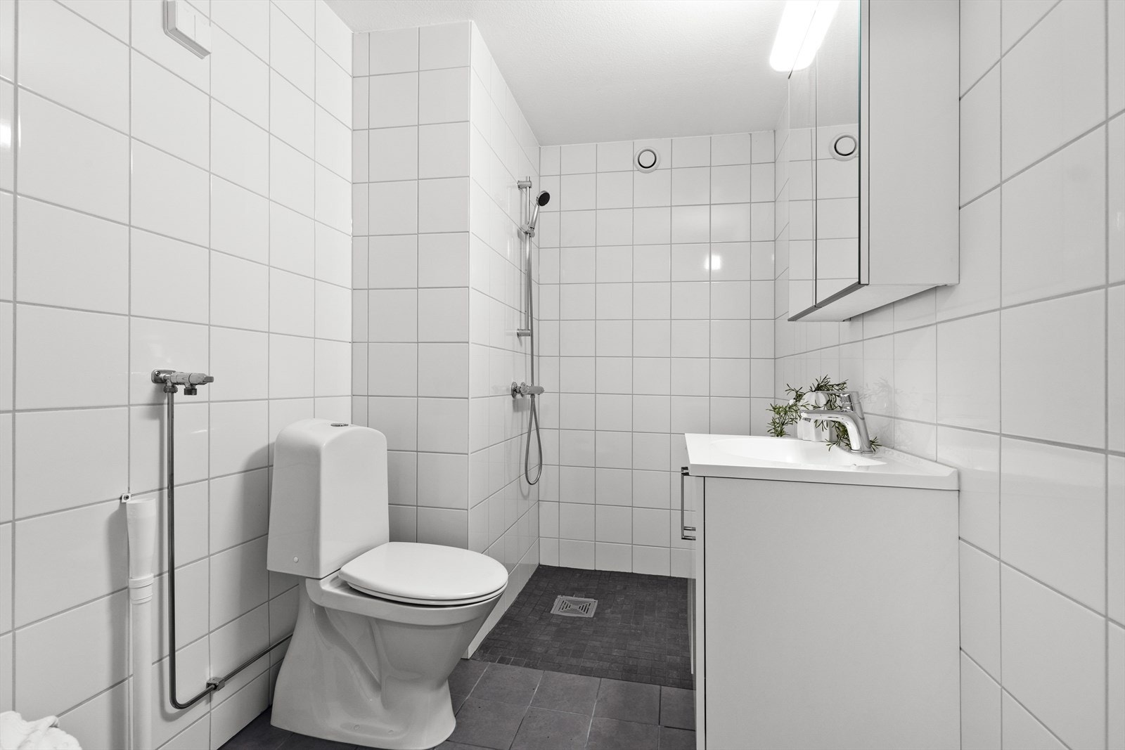 Flislagt bad med dusj, servant, toalett og opplegg for vaskemaskin. Varmekabler i gulv. Galleribilde