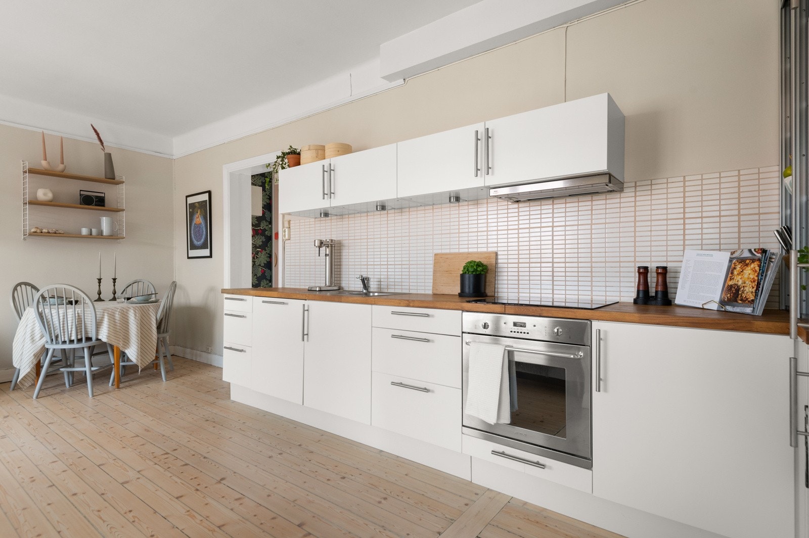 Stilrent kjøkken med hvite, slette fronter og fliser over heltre benkeplate. Kjøkkenet ble oppgradert med nye fronter i 2016. Galleribilde