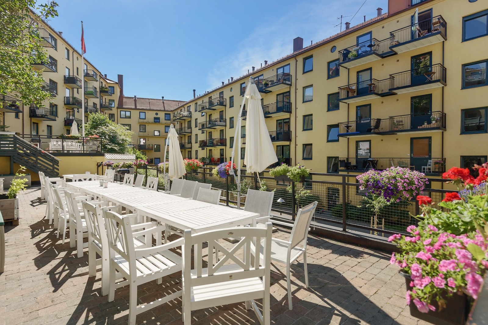 Opphevet nivå hvor det er flere sittegrupper med puter, parasoller og felles griller. Supre solforhold. Galleribilde