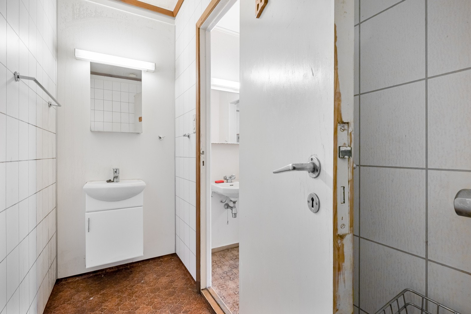 Bad i 1. etasje med belegg på golv, baderomsplater på vegger, dusjoppheng og servantskap. Galleribilde