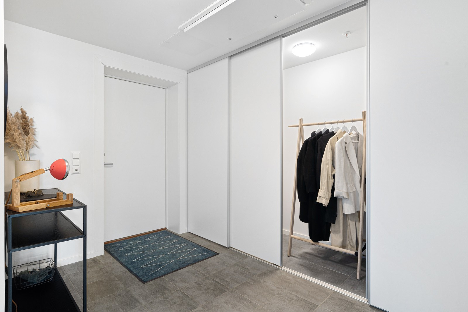 I entréen er det stor skyvedørsgarderobe som fungerer som en innvendig bod