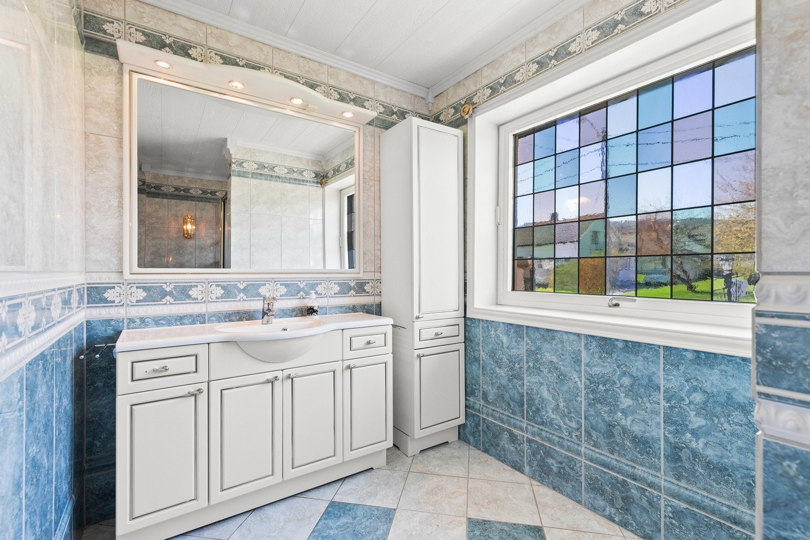 Baderomsinnredningen har hvite, profilerte fronter og består av benkeskap med heldekkende servant. Galleribilde