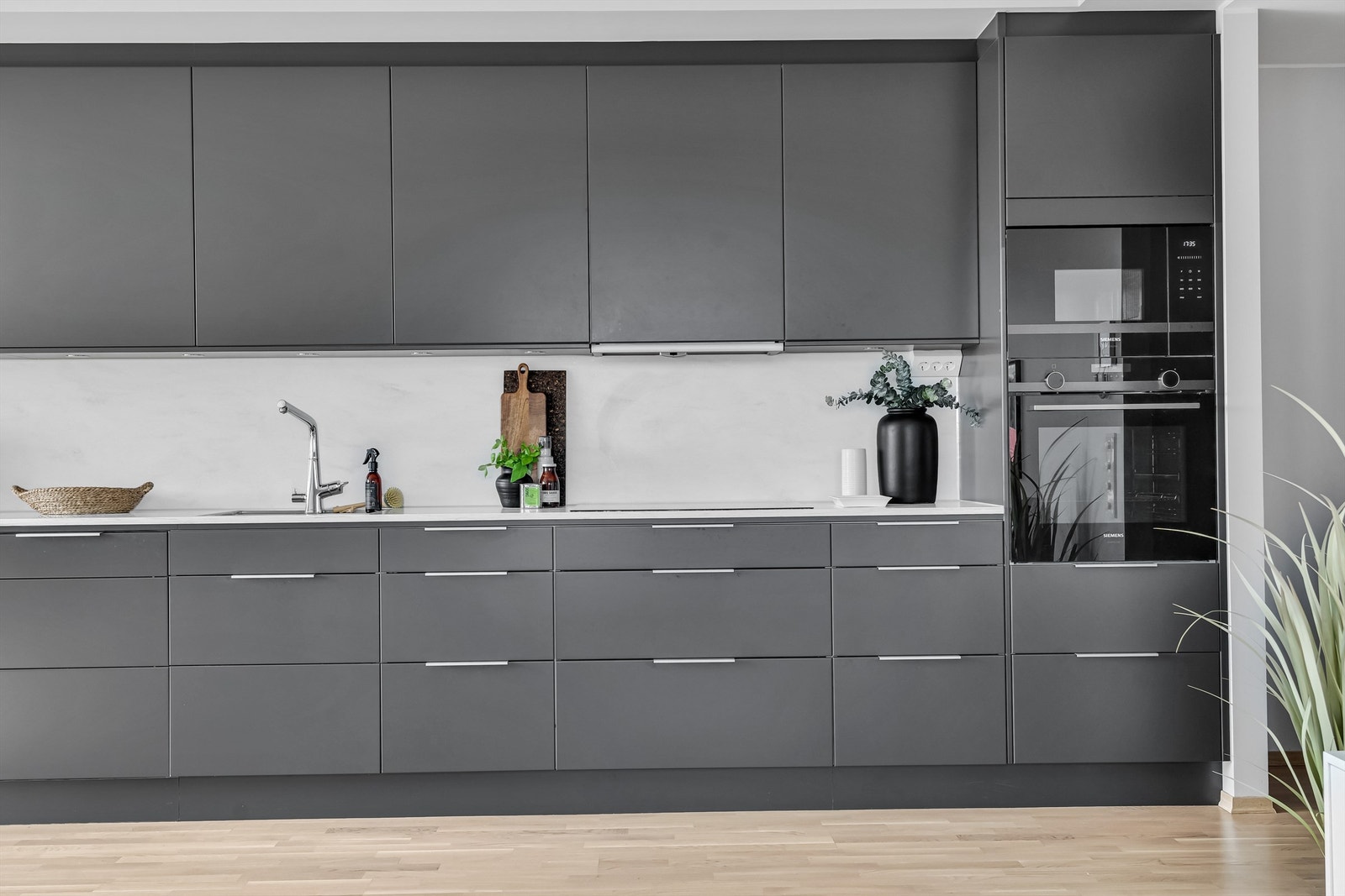 Grå innredning med glatte skapfronter, corian benkeplate, nedfelt rustfri oppvaskkum og et-greps armatur Galleribilde