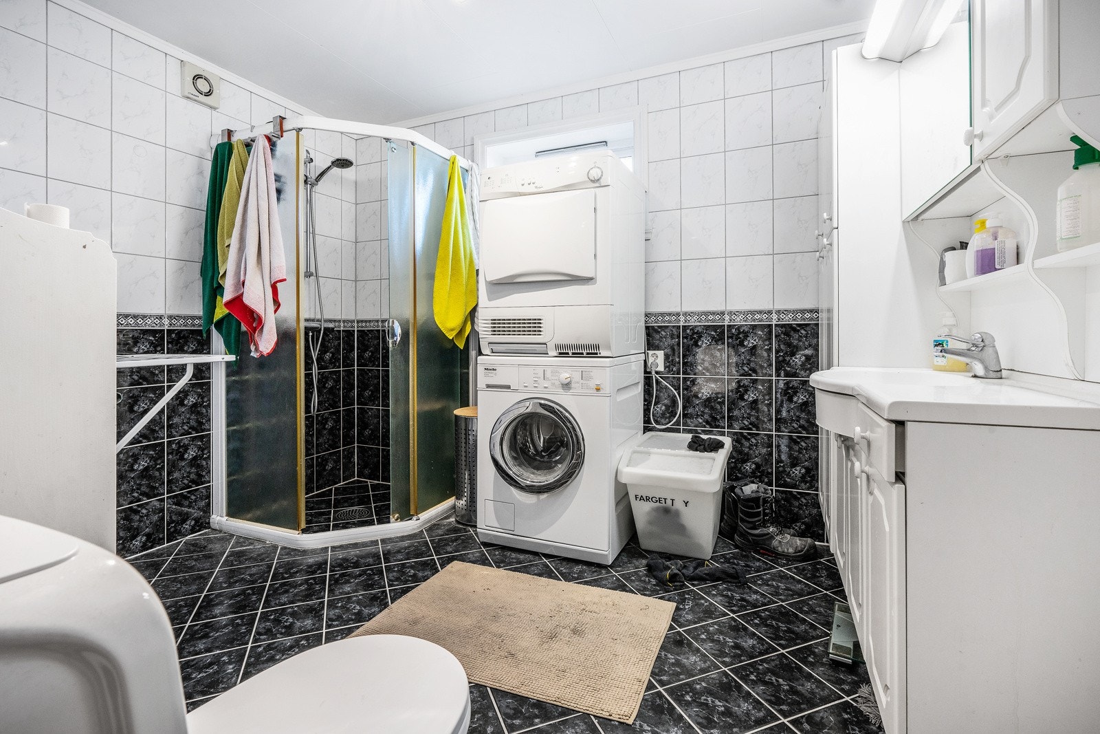 Romslig bad med fliser på gulv og vegger, og opplegg for vaskemaskin Galleribilde