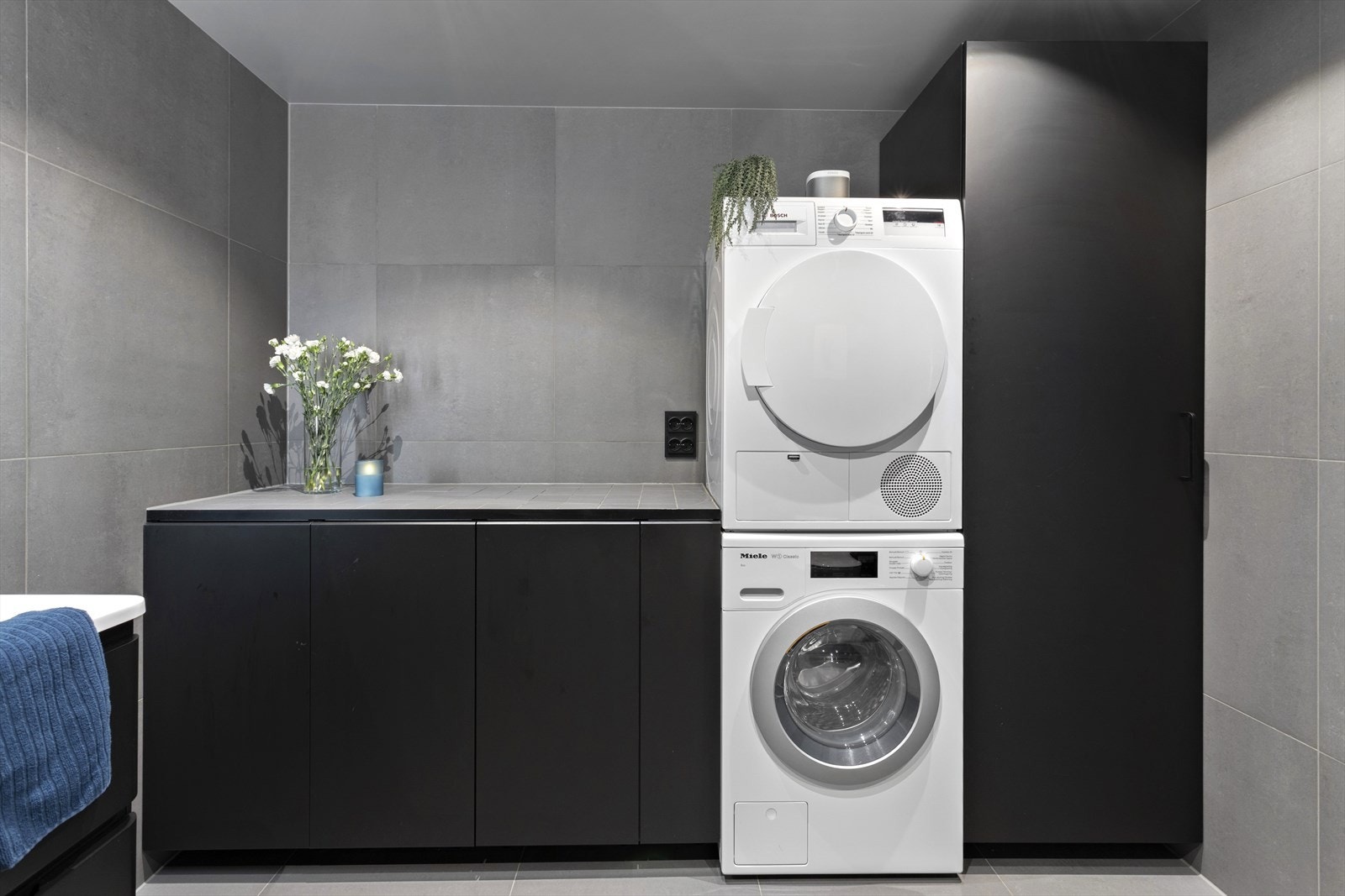 Praktisk benk med oppbevaring under og innredet plass for vaskemaskin og tørketrommel. Galleribilde