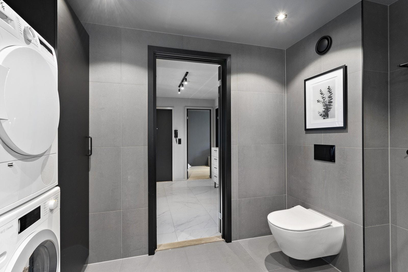 Badet er innredet med vegghengt toalett, servant med underskap, speil, brettebenk med underskap, høyskap, skjermet dusjhjørne av herdet glass, regndusj og dusjgarnityr. Galleribilde