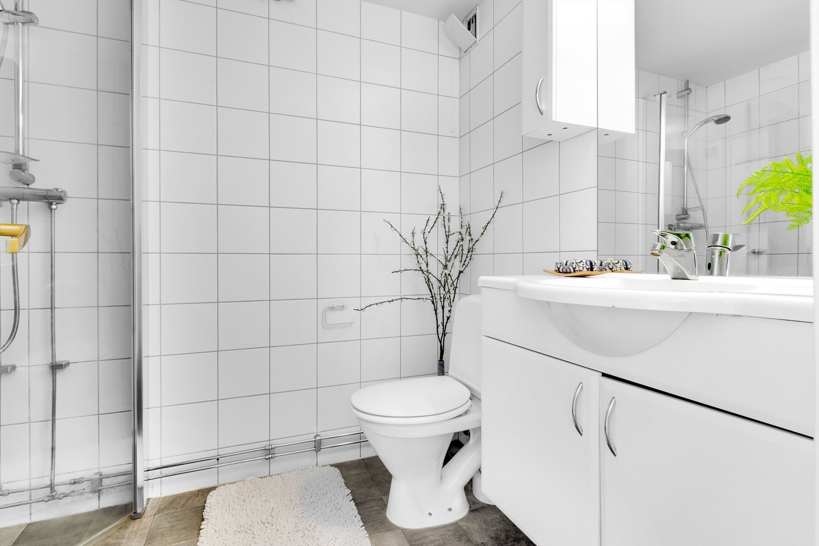 Flislagt bad med varmekabler. Opplegg for vaskemaskin. Hel servantplate med servantskap, 2 overskap og speil. Toalett. Hjørnedusj med innfellbare glassdører. Naturlig avtrekk. Galleribilde