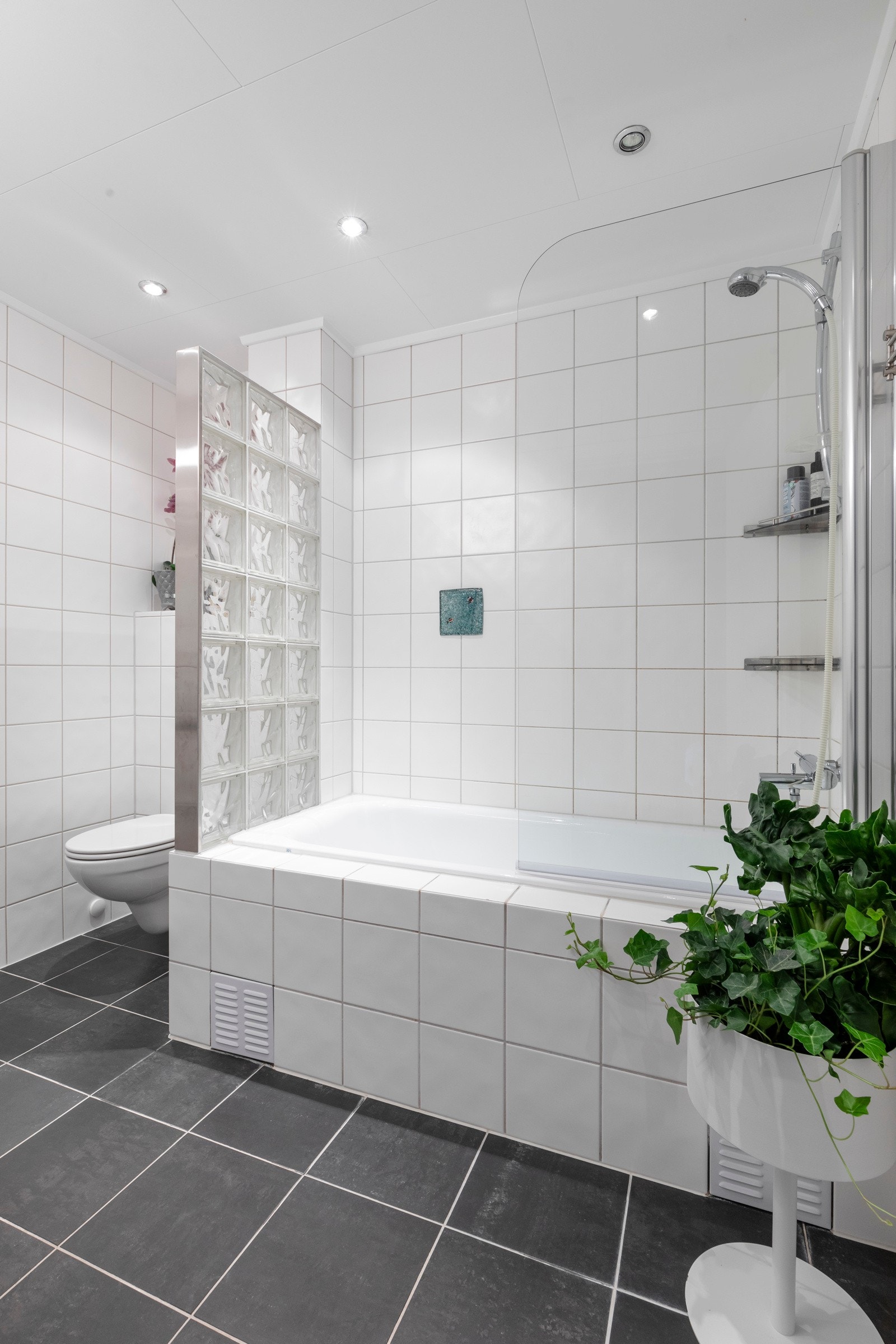 Badet har flislagt gulv med varmekabler, flislagte vegger og nedsenket himling med downlights. Galleribilde