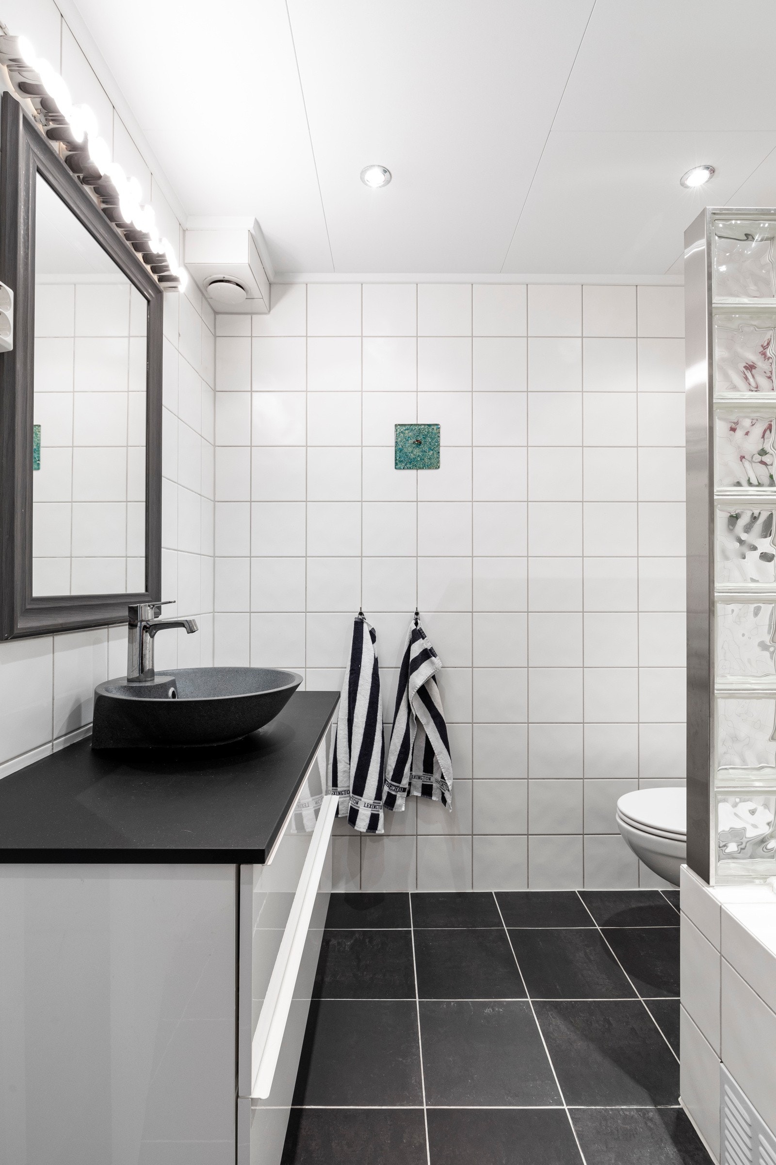 Behagelig og tidløse fliser. Fin servantinnredning og badekar med delevegger av glass og glassbyggerstein. Galleribilde