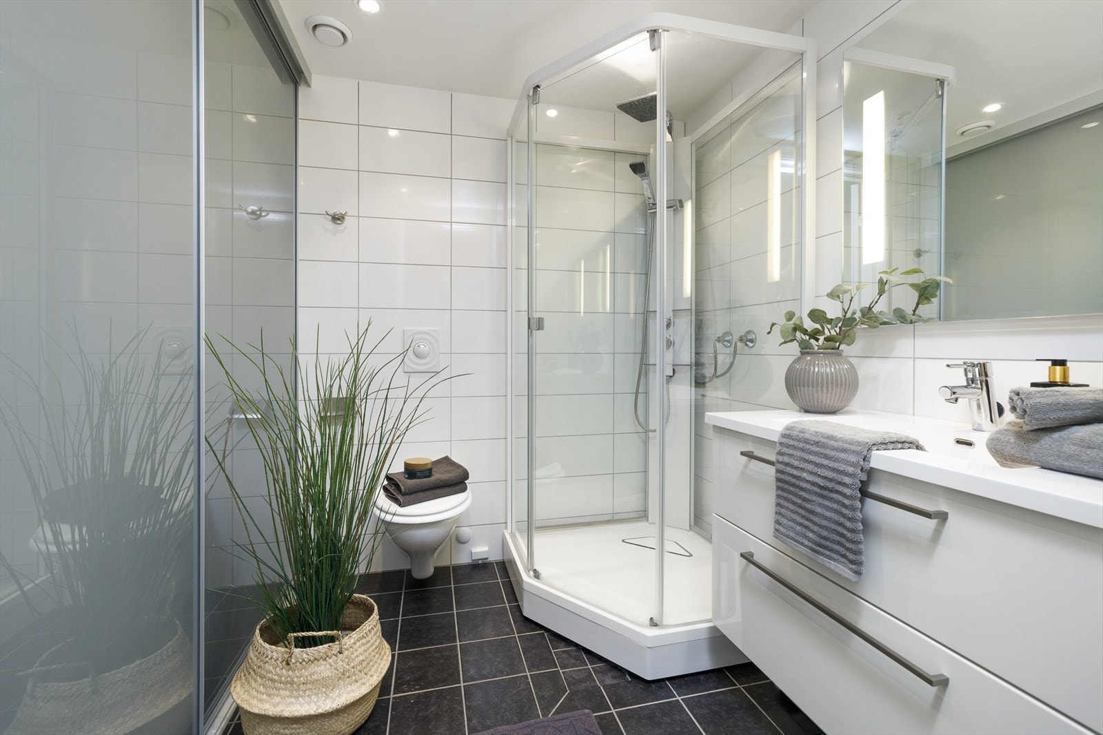 Stilrent bad med opplegg for vaskemaskin og tørketrommel som er diskre plassert bak skyvedørene. Galleribilde