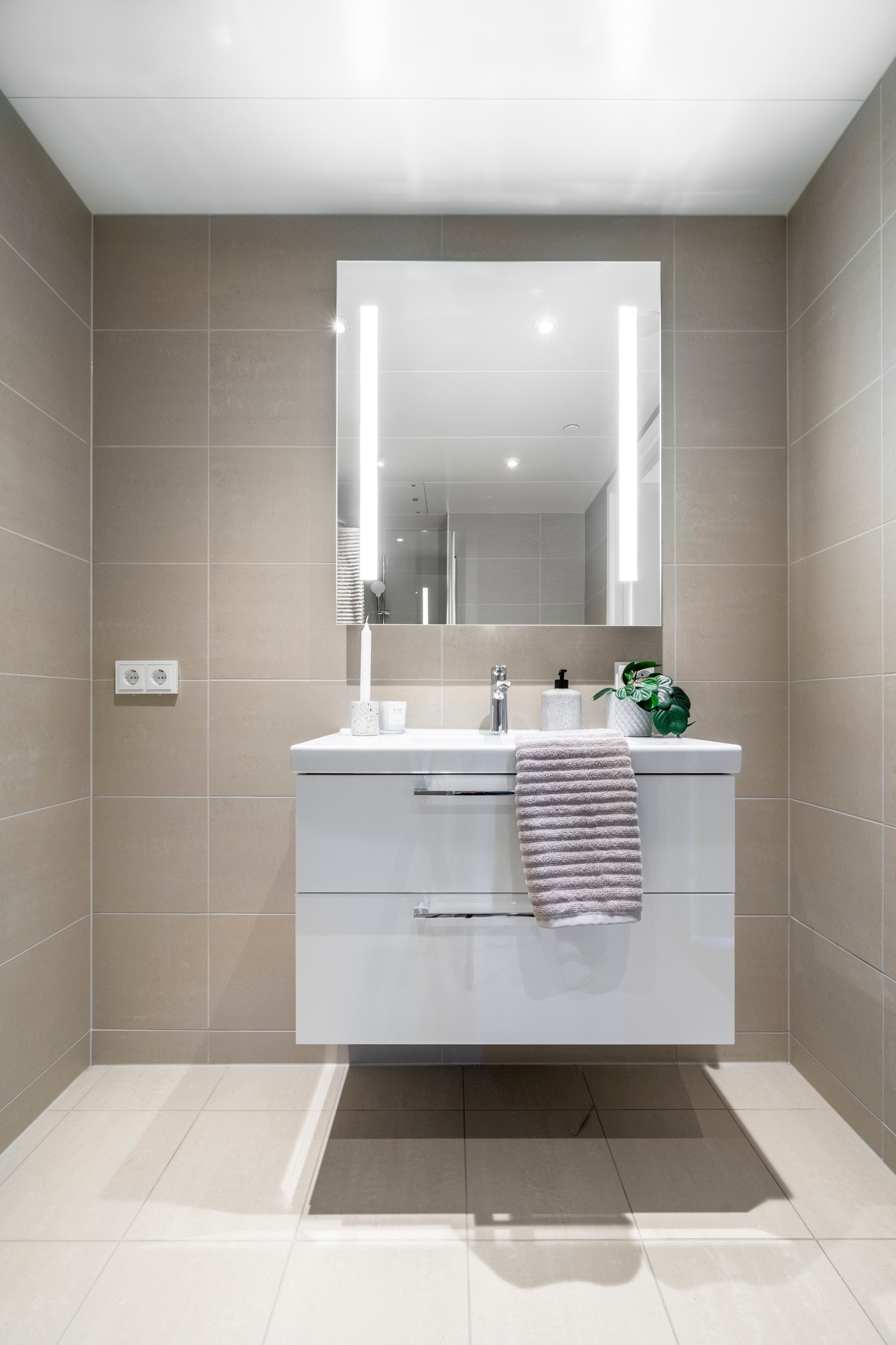 Badet er av god størrelse med nedfelt servant i benkeplate, hvitt servantskap med profilerte fronter og speil med innfelte lys Galleribilde
