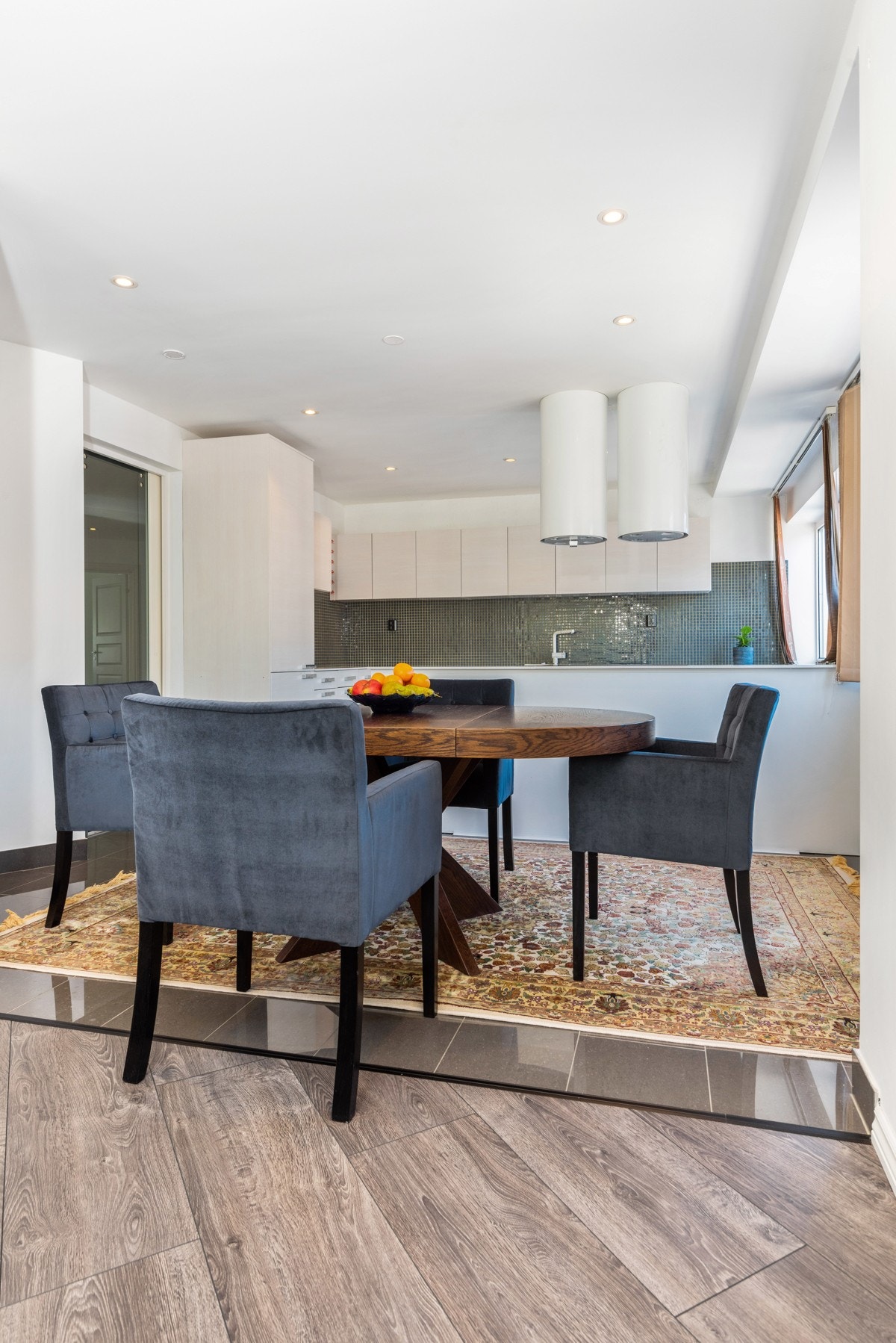 Her er det hvit kjøkkeninnredning fra Sigdal med benkeplate i stein, integrerte hvitevarer, mekanisk avtrekk og mosaikkfliser mellom over -og underskap. Galleribilde