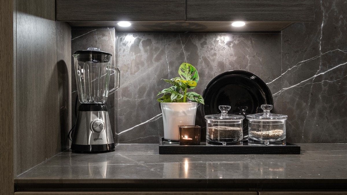 Den stilige, italienske benkeplaten i marmor strekker seg langs veggen og gir kjøkkenet et lekkert og gjennomført uttrykk Galleribilde