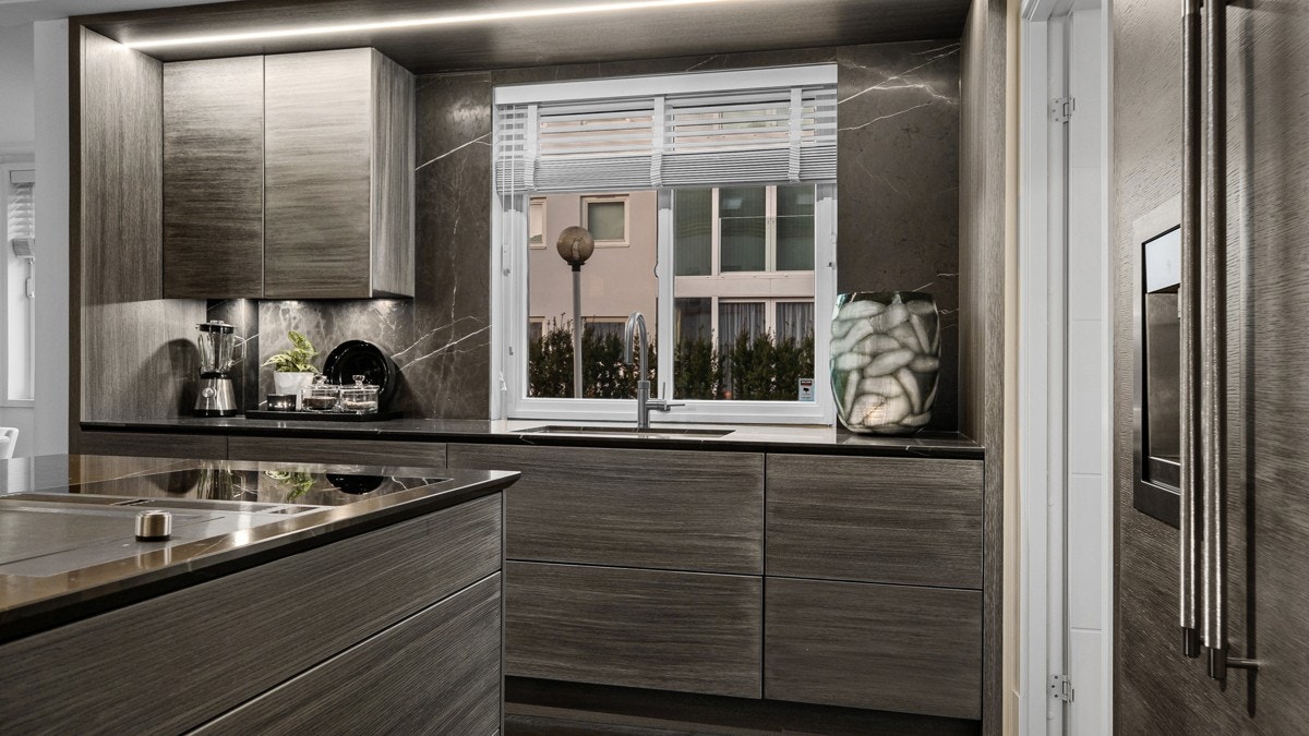 Den snekkerbygde kjøkkeninnredningen fra 2019 står frem som et smykke i rommet, med stram stil og mørke toner Galleribilde