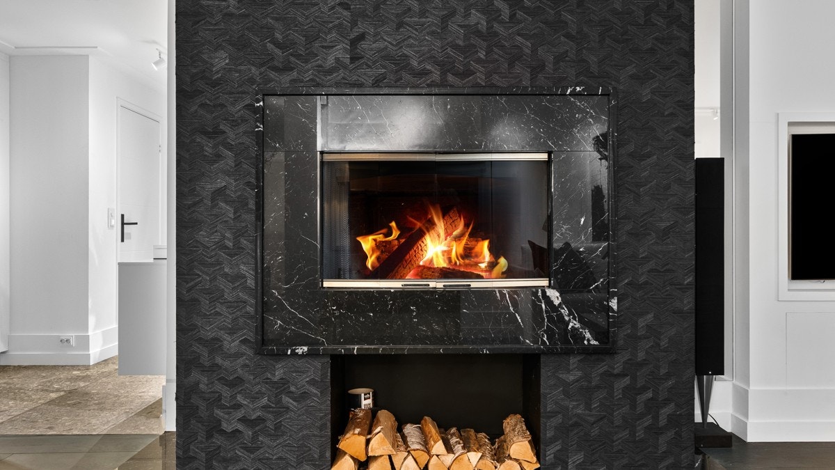 En dekorativ peis med sort omramming gir spiseplassen et lunt blikkfang, og godt med varme Galleribilde