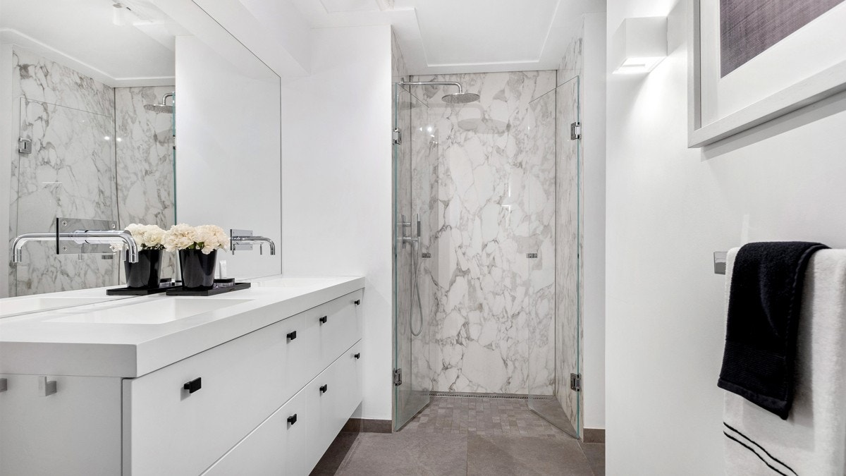 Baderommet har to innganger, både via hovedsoverommet og kjøkkenet, og er innredet med en romslig regnfallsdusj, benkeplate i corian, dobbelservant med underskap fra Huseby Galleribilde