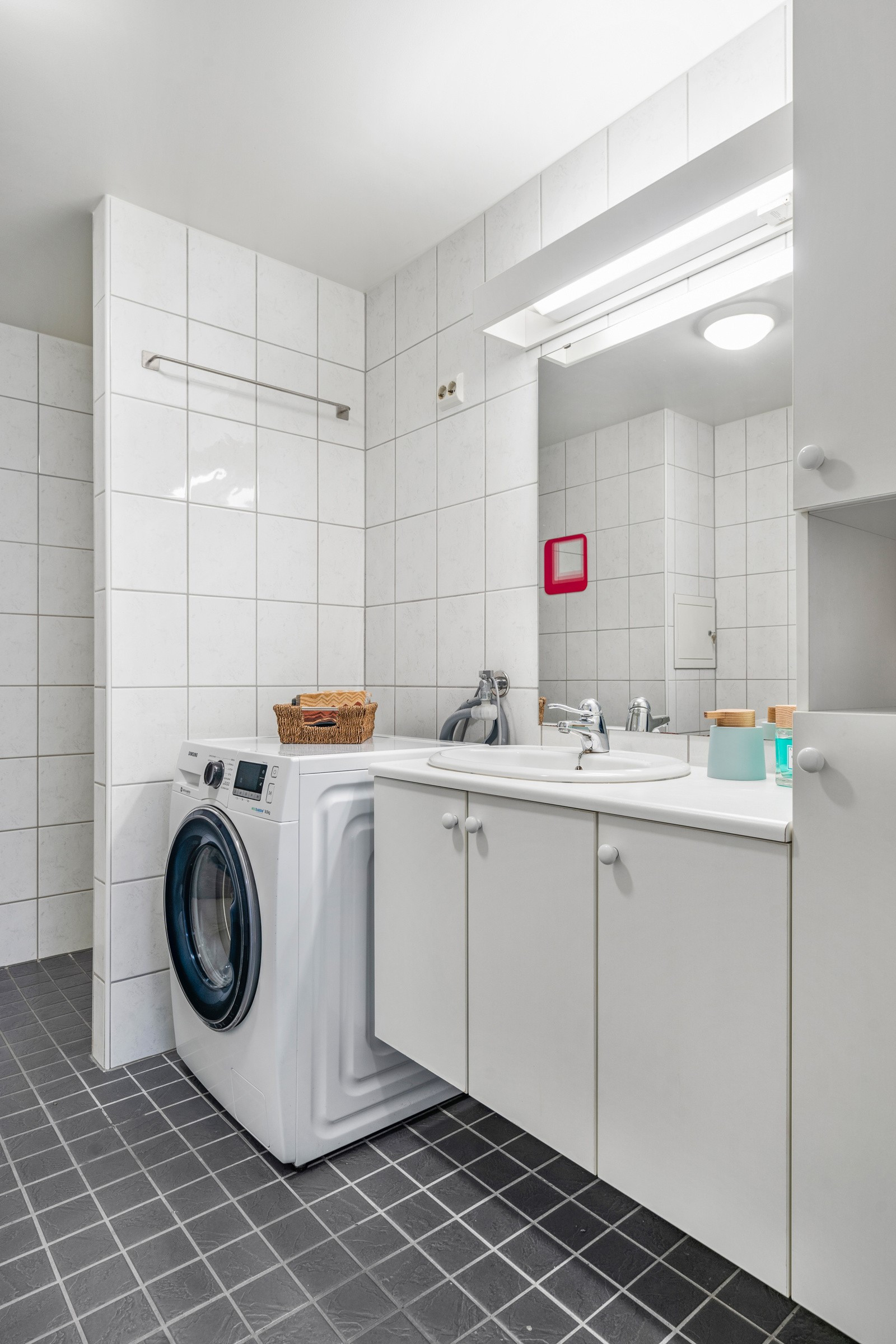 Badet er innredet med dusjnisje, servant og toalett - her er det også opplegg for vaskemaskin