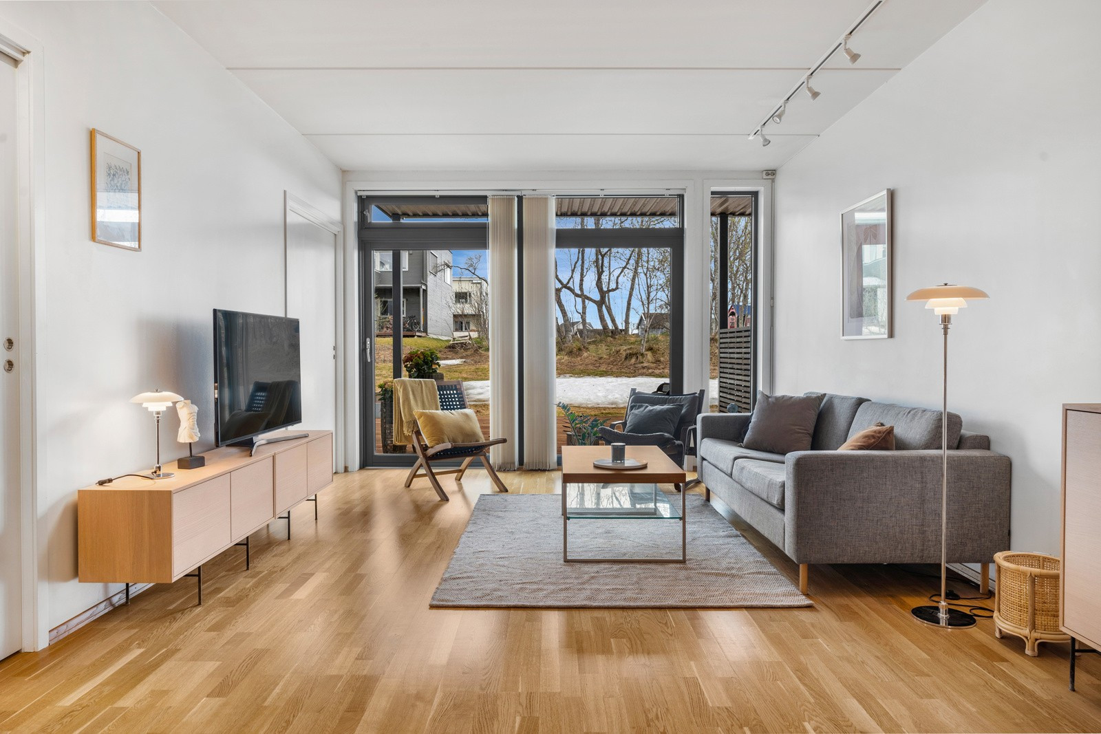 Her finner du en lys og delikat stue med plass til stor sofa - her er det også utgang til behagelig markterrasse