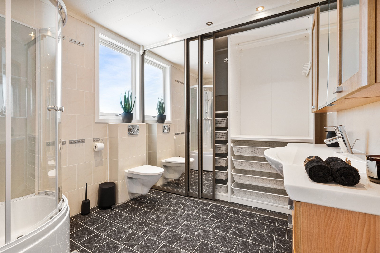 Badet er komplett flislagt med gulvvarme - her er det også en svært praktisk skyvedørsgarderobe for oppbevaring!