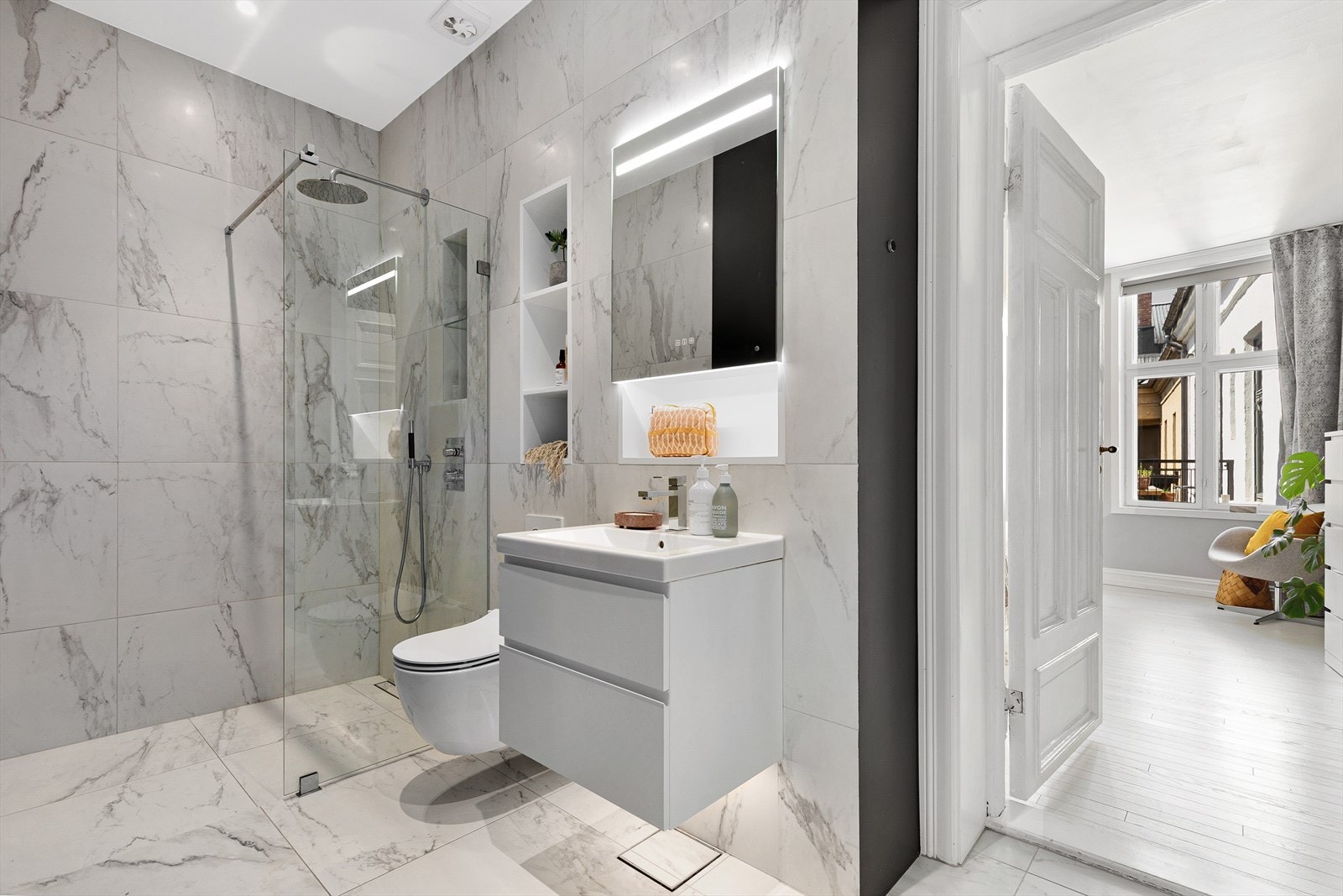 Lekkert baderom fra 2020 med flislagt gulv med varme og flislagte/malte vegger. Nedsenket himling med downlights og integrerte høyttalere Galleribilde