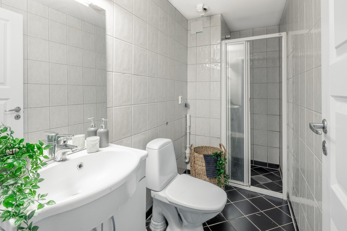 Helfliset bad på 3,40 kvm, innredet med servant i møbel, toalett og dusjnisje med skyvedører Galleribilde