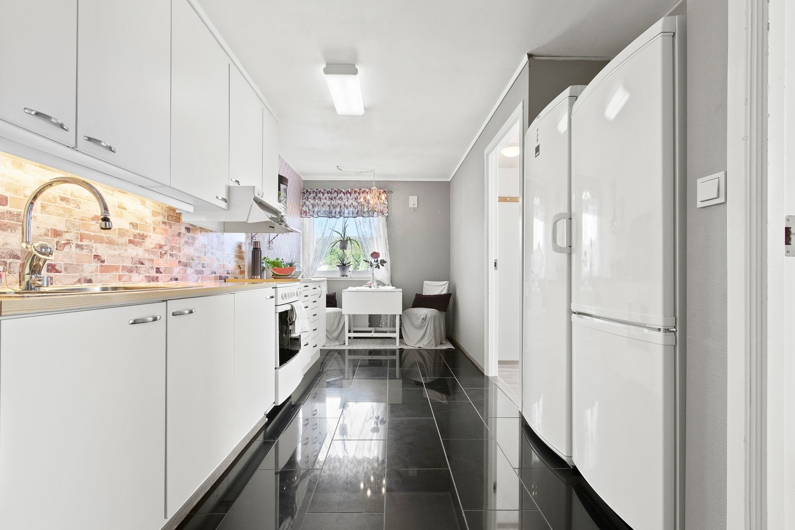 Kjøkkenet har en avlang form med plass til et lite spisebord ved vinduet. Galleribilde