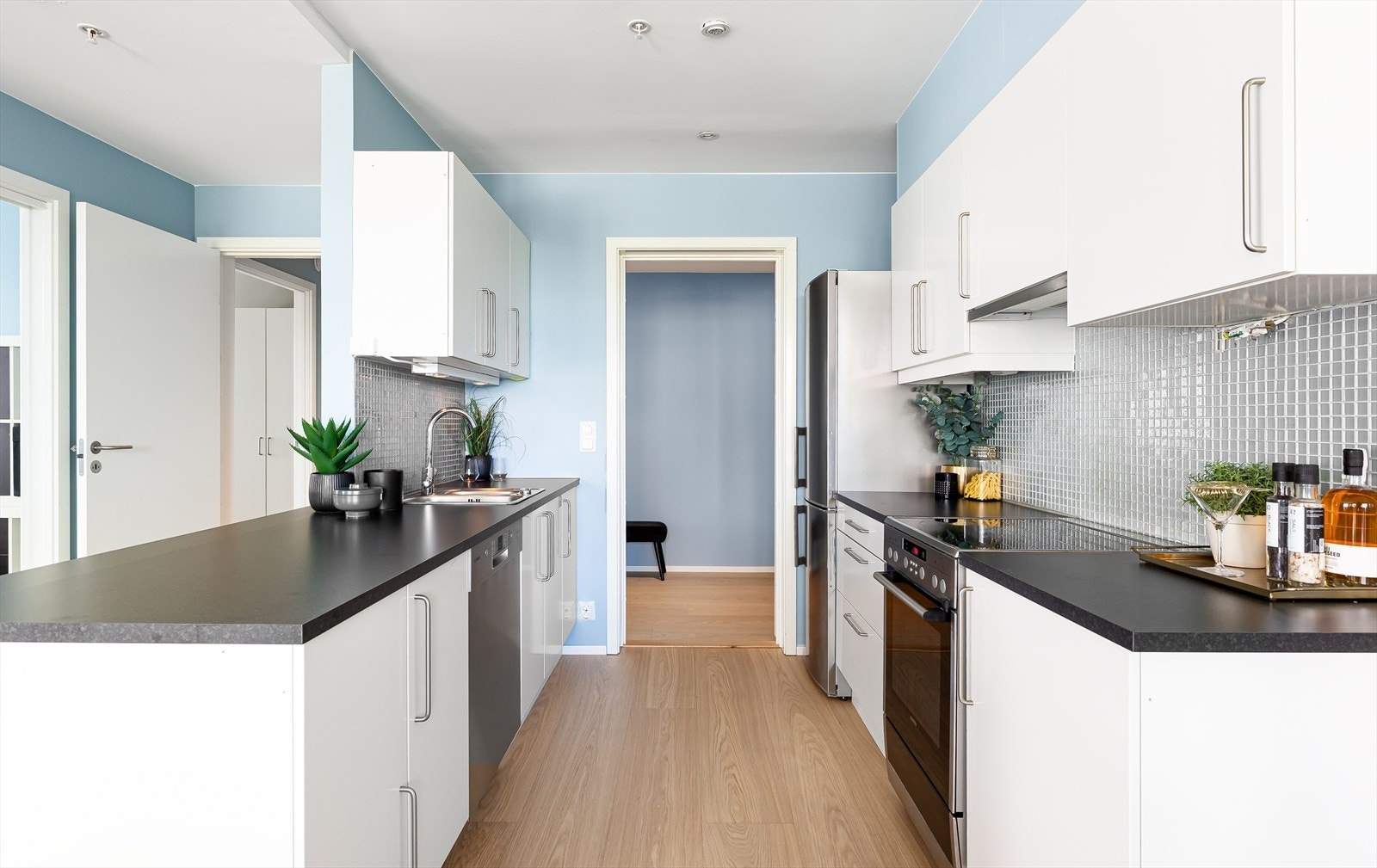 Kjøkkeninnredning med hvite folierte glatte fronter. Benkeplate (fra 2021) med nedfeldt vaskekum. Tilpasset komfyr og oppvaskmaskin. Galleribilde