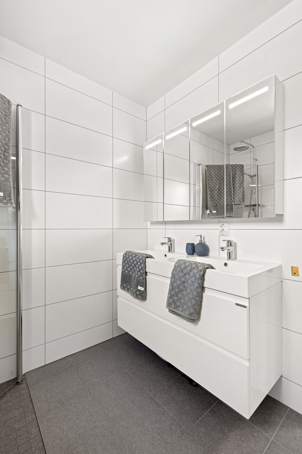 Innredningen består av dobbelt servantskap fra Viningbad, 2 servanter, speilskap med lys.Videre er det dusj med dører, vegghengt toalett og opplegg for vaskemaskin, samt plass til tørketrommel. Galleribilde