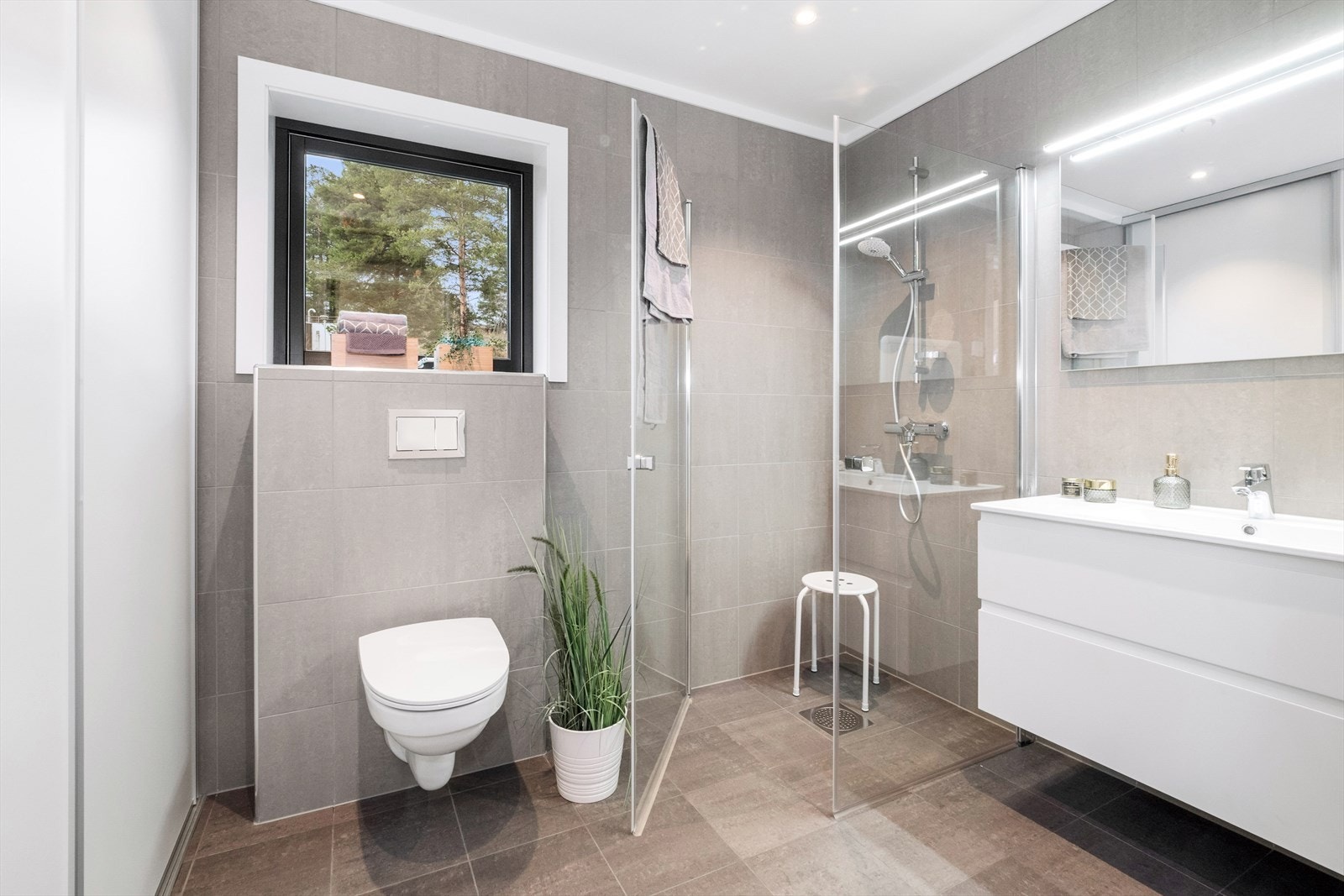 Badet har mørkegrå fliser av typen Marthe Antrachite på gulv, og veggene med Marthe Grå fliser. Galleribilde