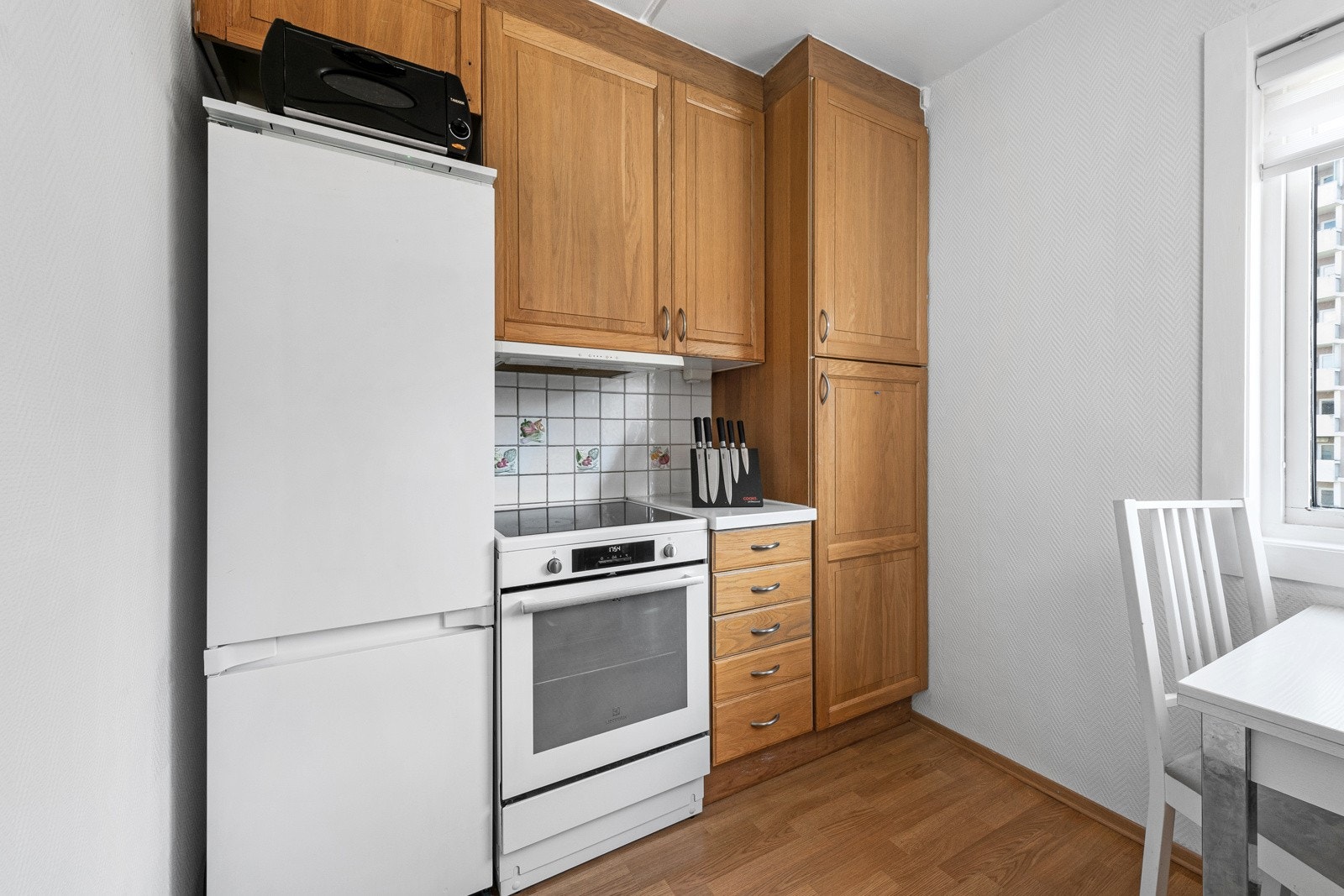 Benkeplaten er i laminat, med dobbel vaskekum, og det er hvite fliser med dekor på veggene i bakkant. Galleribilde