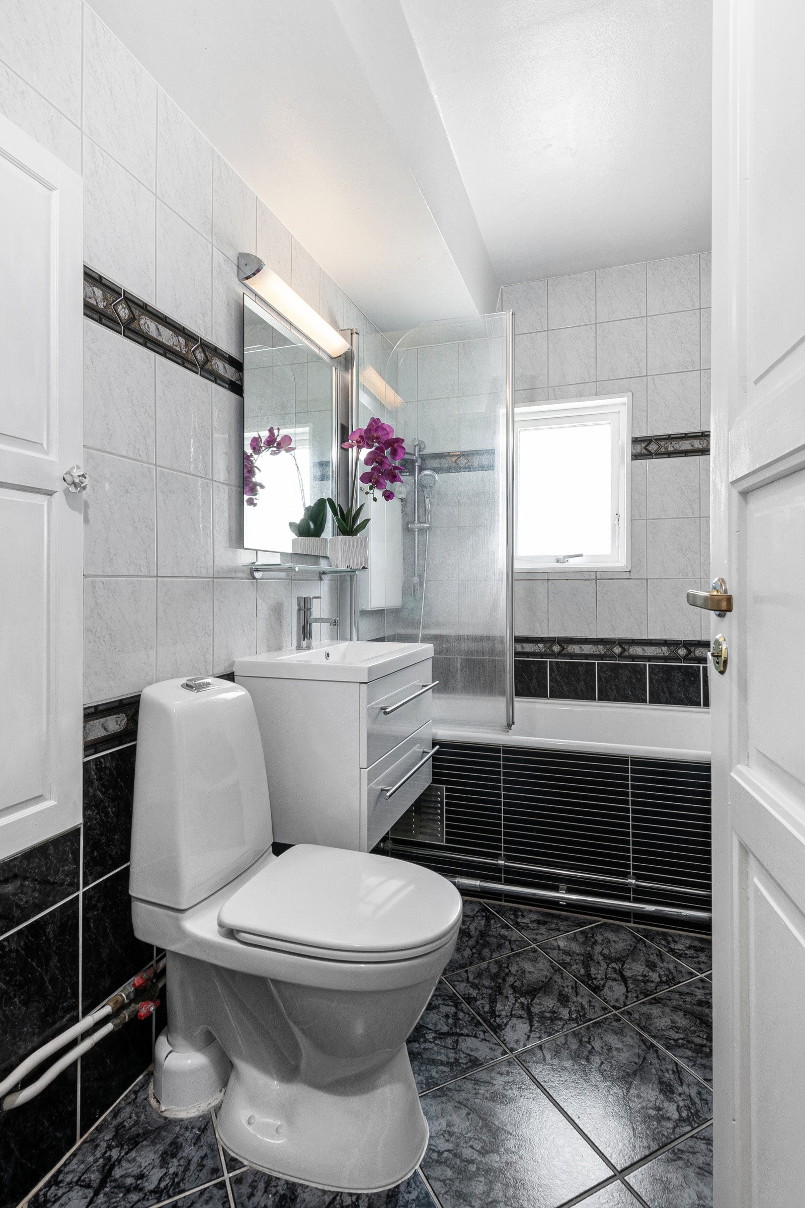 Badet har velholdte fliser i sort og grått, med varme i gulv. Galleribilde