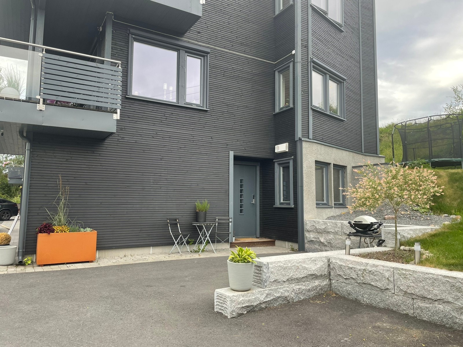 Inngangsparti med biloppstillingsplass og cafésett. Galleribilde
