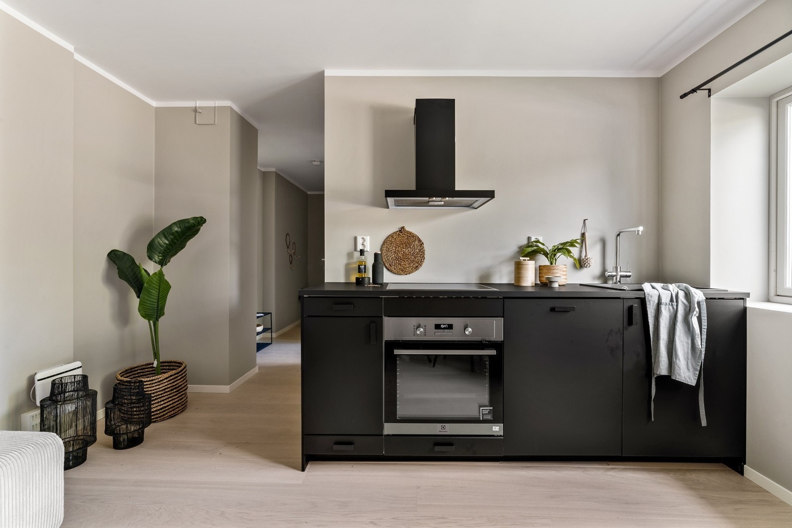 Kjøkkeninnredning med glatte svarte fronter og laminert benkeplate med kjøkkenvask. Integrert platetopp m/induksjon, stekeovn og oppvaskmaskin. Galleribilde