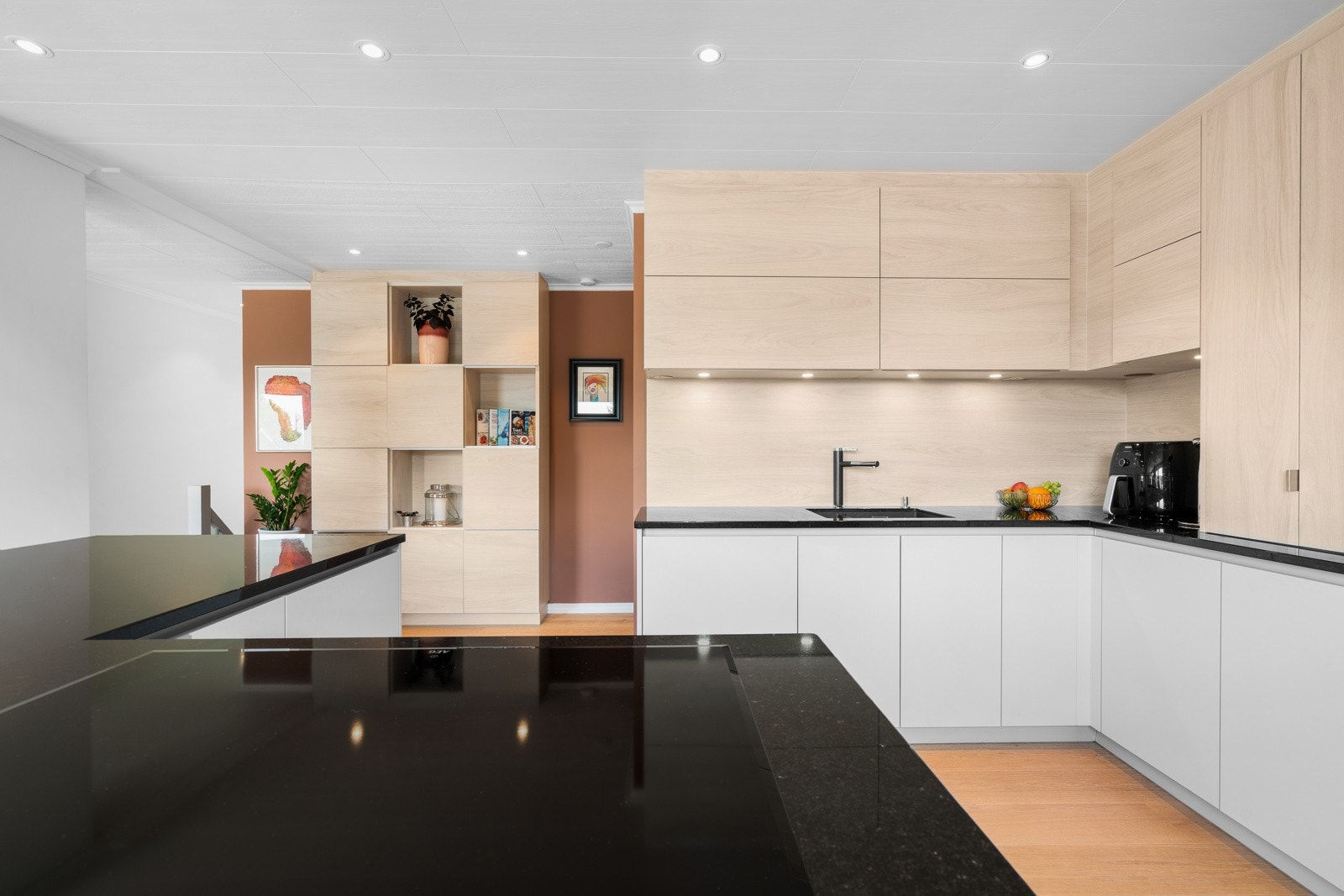 Innredningen har takhøye skap, granittbenkeplater og en vinklet kjøkkenøy med kokesone. Galleribilde