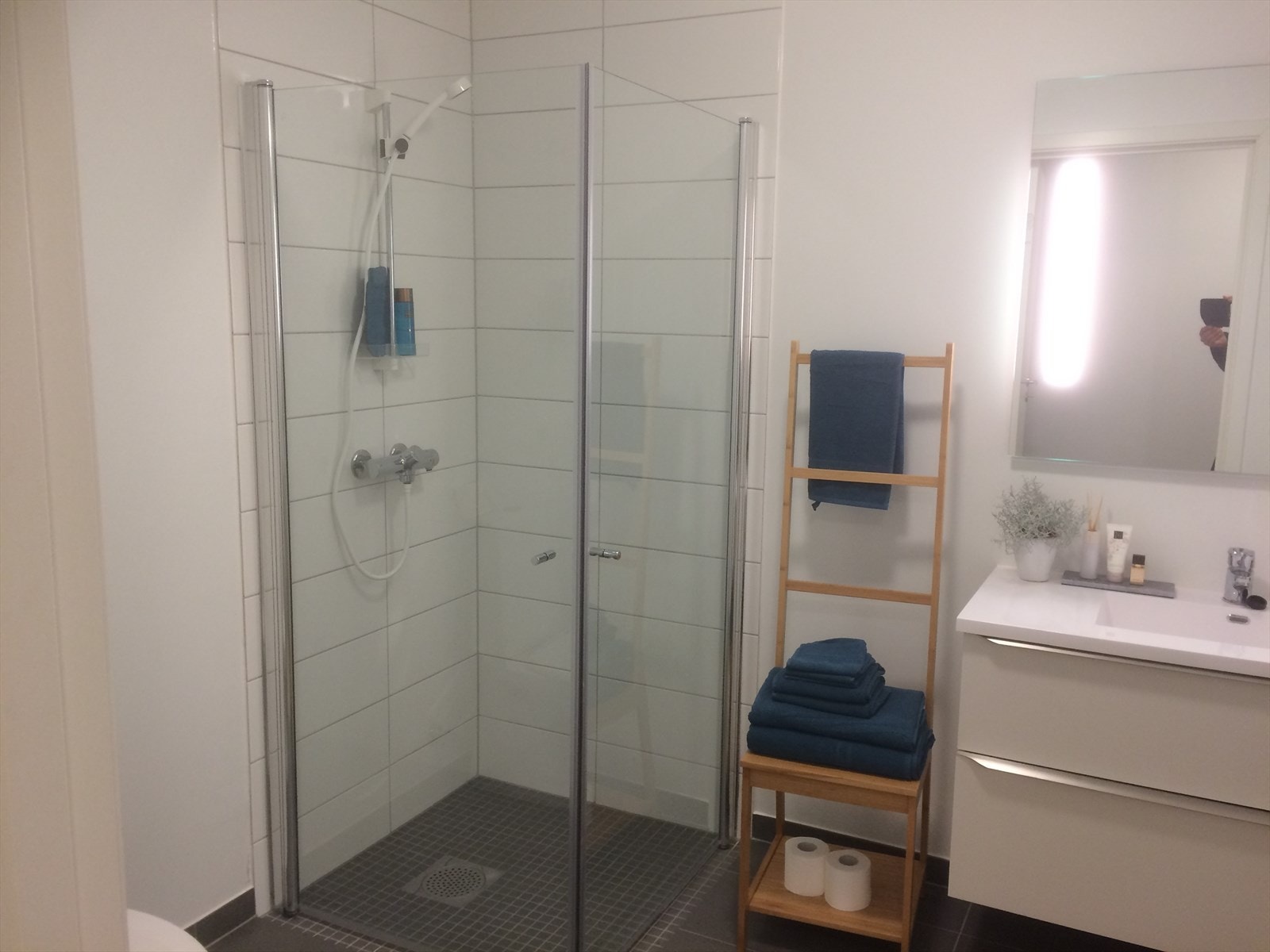 Delikat flislagt bad med dusjnisje, WC og baderomsinnredning fra HTH. Opplegg for vaskemaskin bak smart og plassbesparende skyvedørsløsning. Galleribilde