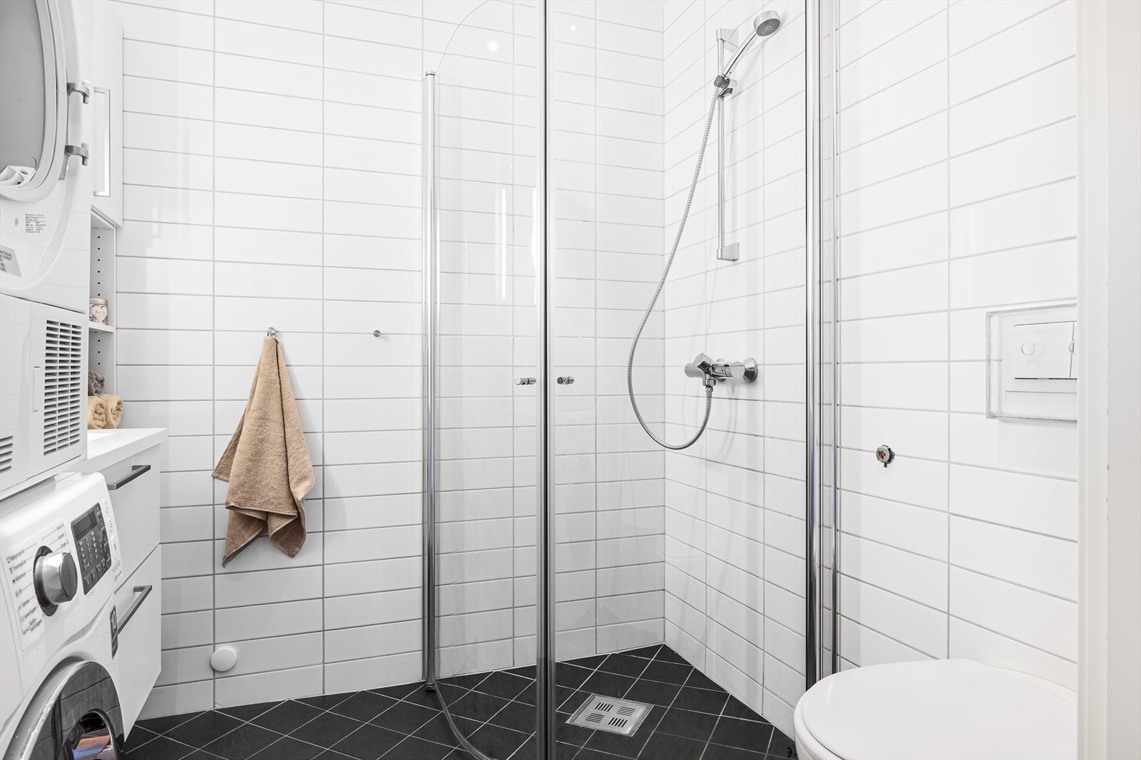 Badet er utstyrt med dusjhjørne, vegghengt klosett, servantmøbler, høyskap, speil med integrert belysning og opplegg for vaskemaskin på bad. Galleribilde