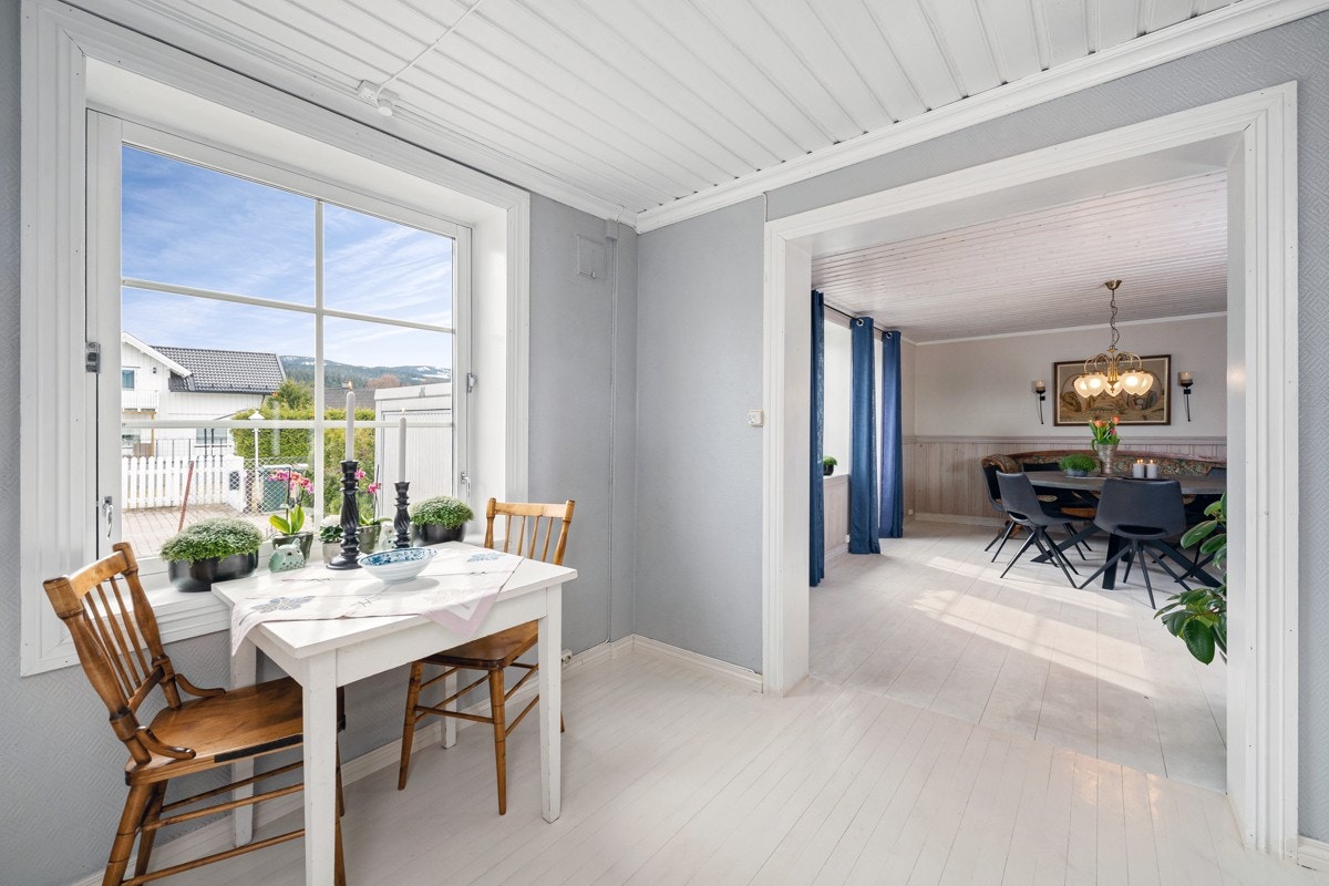 Kjøkkenet har en bred åpning til stuen og frokostplass ved vinduet. Galleribilde