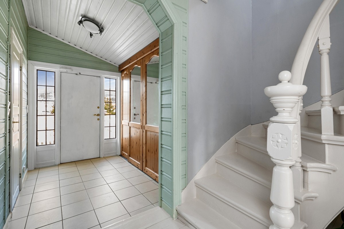 Vel innenfor er det en entré med skråtak, grønnmalte panelvegger og fliser på gulv med vannbåren gulvvarme. Galleribilde