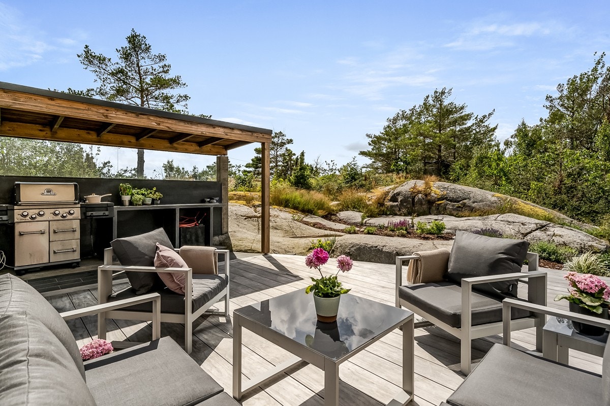 Uteplassene finnes på alle kanter av boligen - her ser du uteplassen som er laget til med tanke på hyggelige måltider i sola sommerstid. Galleribilde